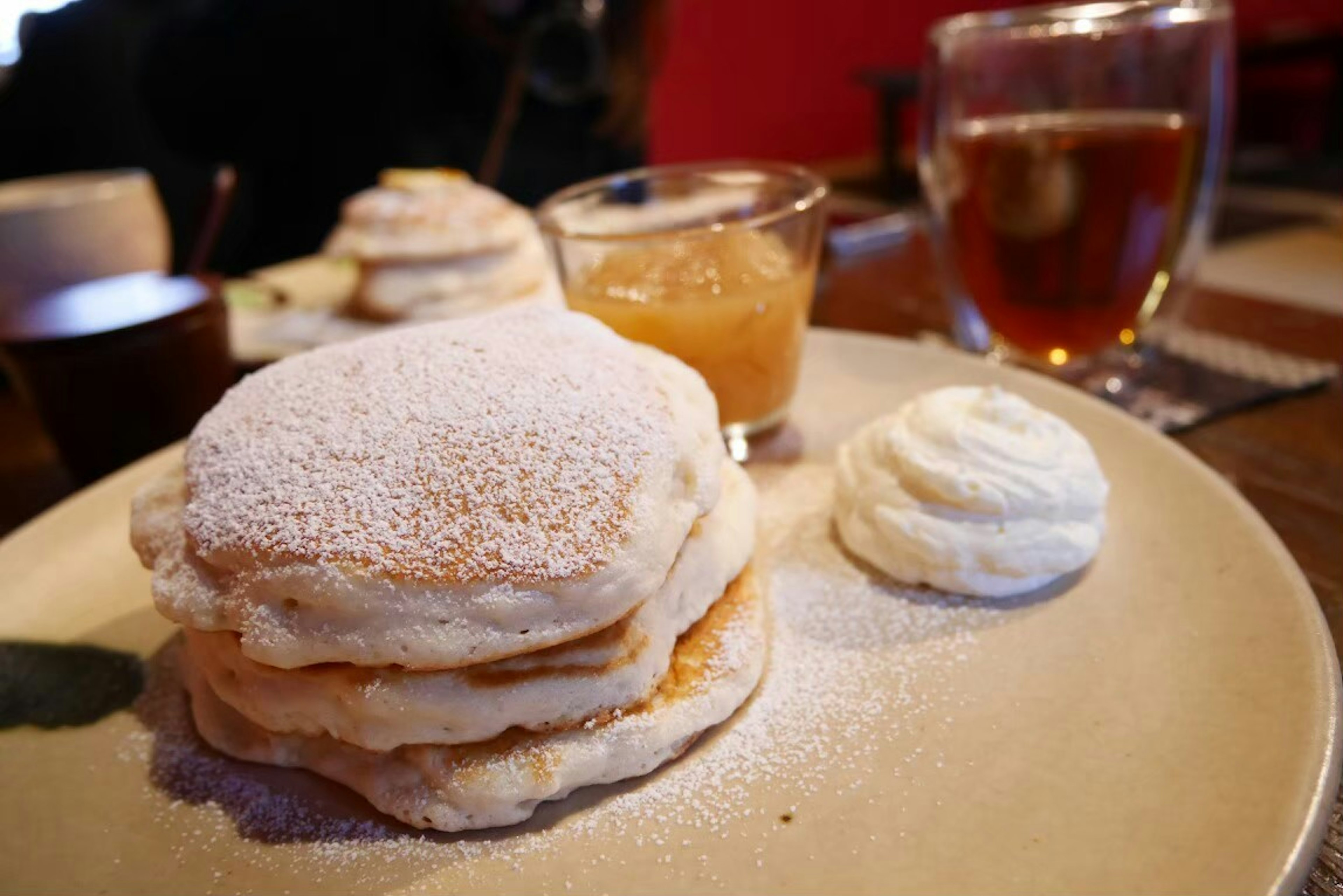 Fluffige Pfannkuchen mit Sahne und Fruchtsauce auf einem Teller