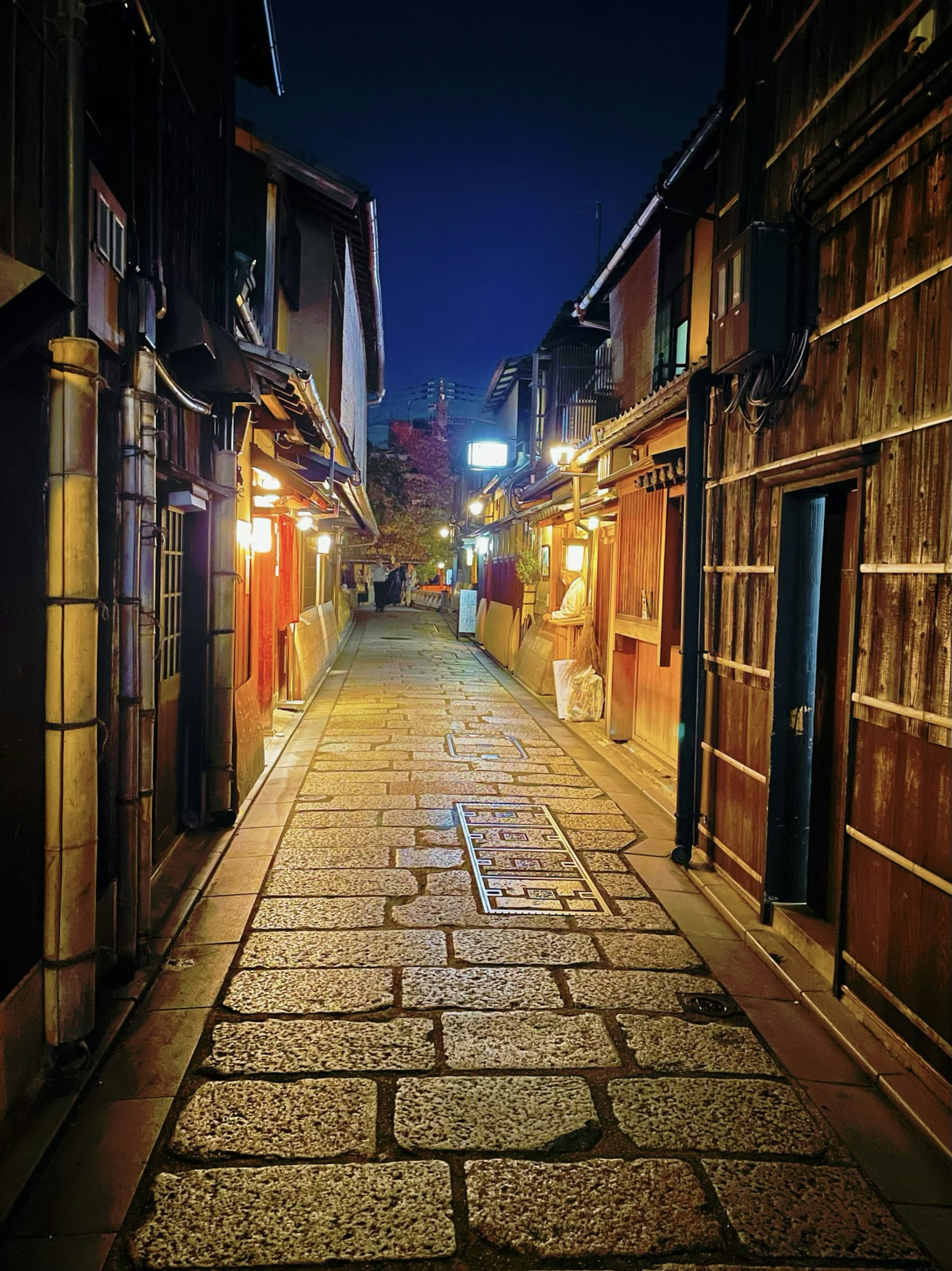 Schmale steingepflasterte Gasse bei Nacht mit traditionellen Holzbauten