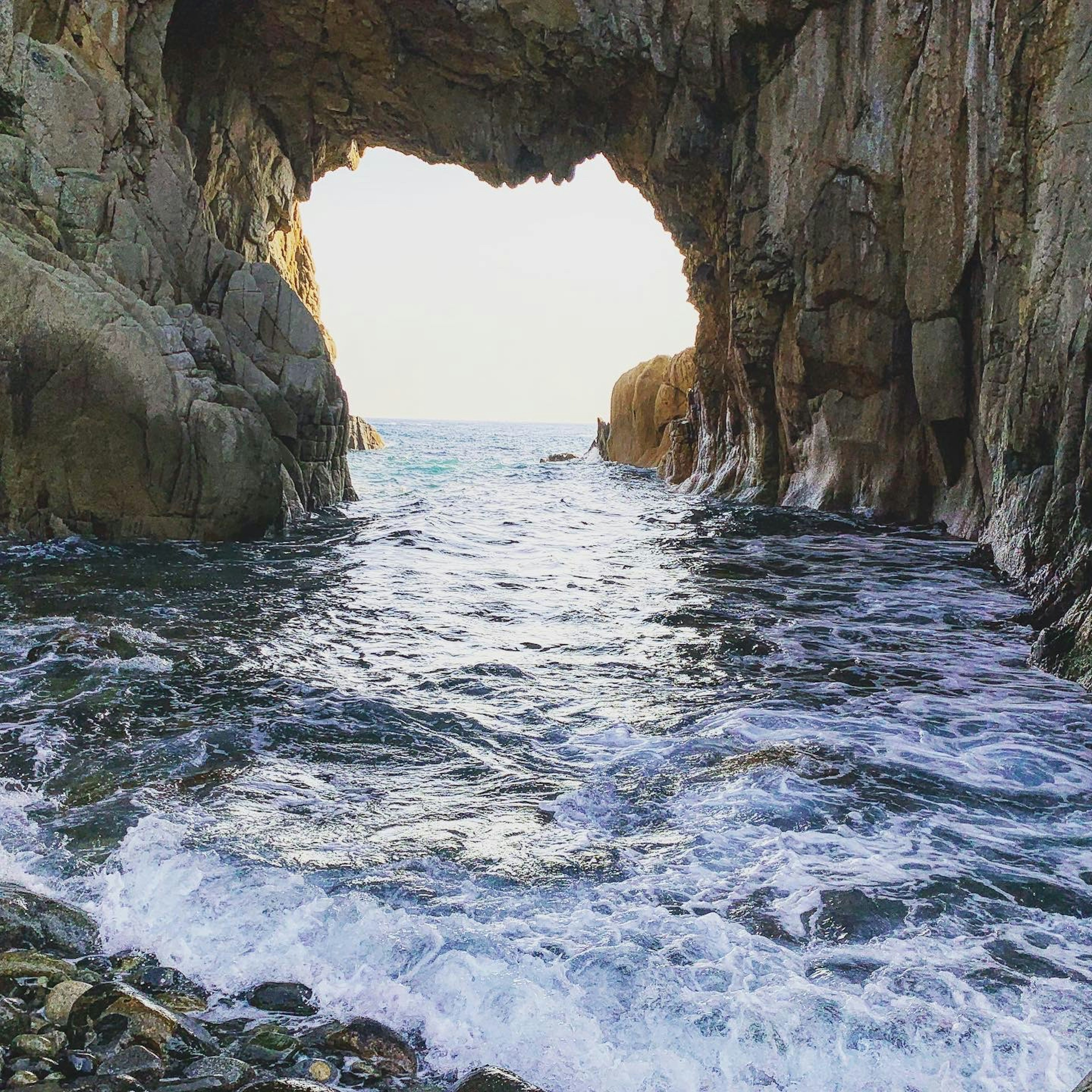 View of the ocean through a rocky arch with waves