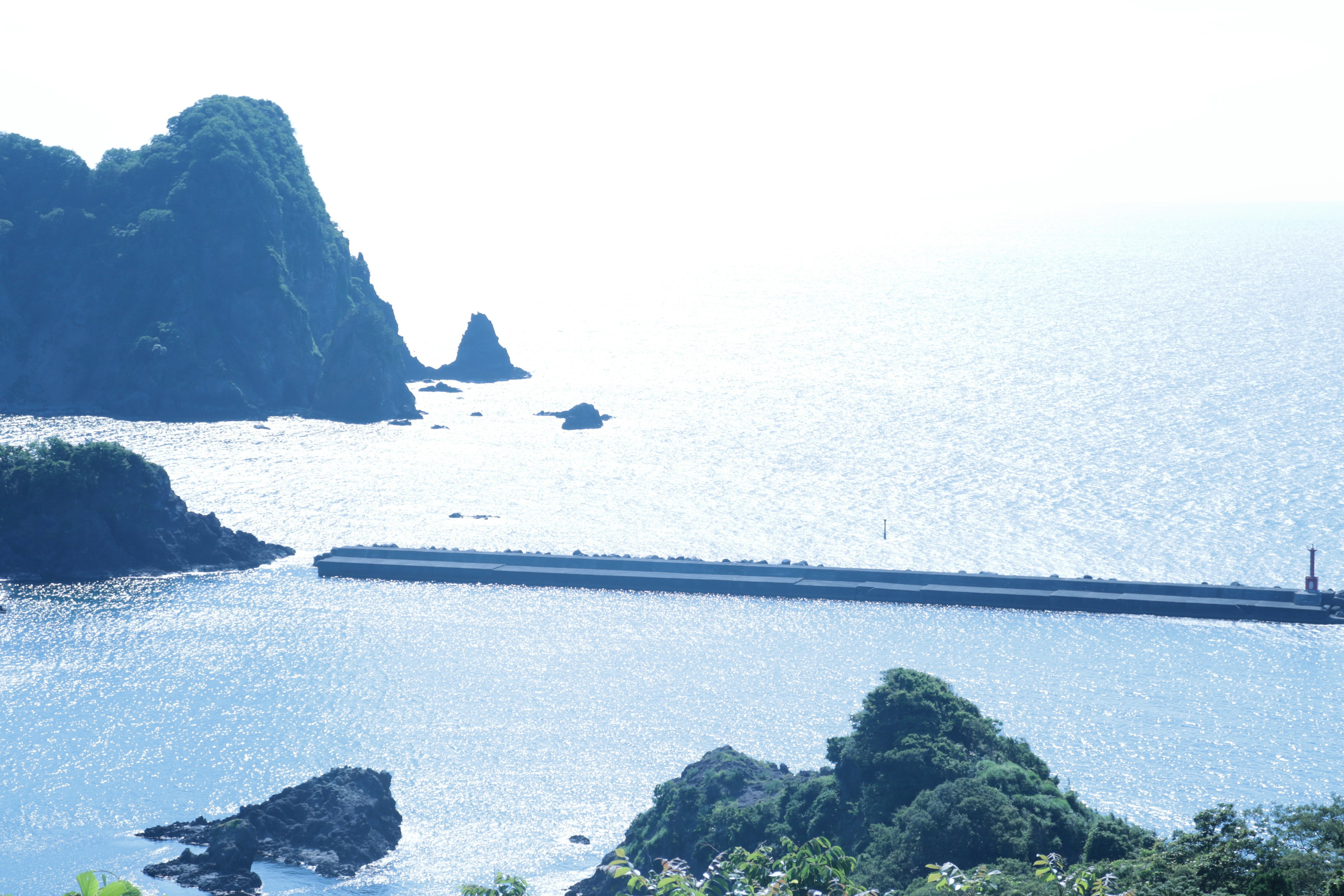 Vista costera con un rompeolas e islas distantes