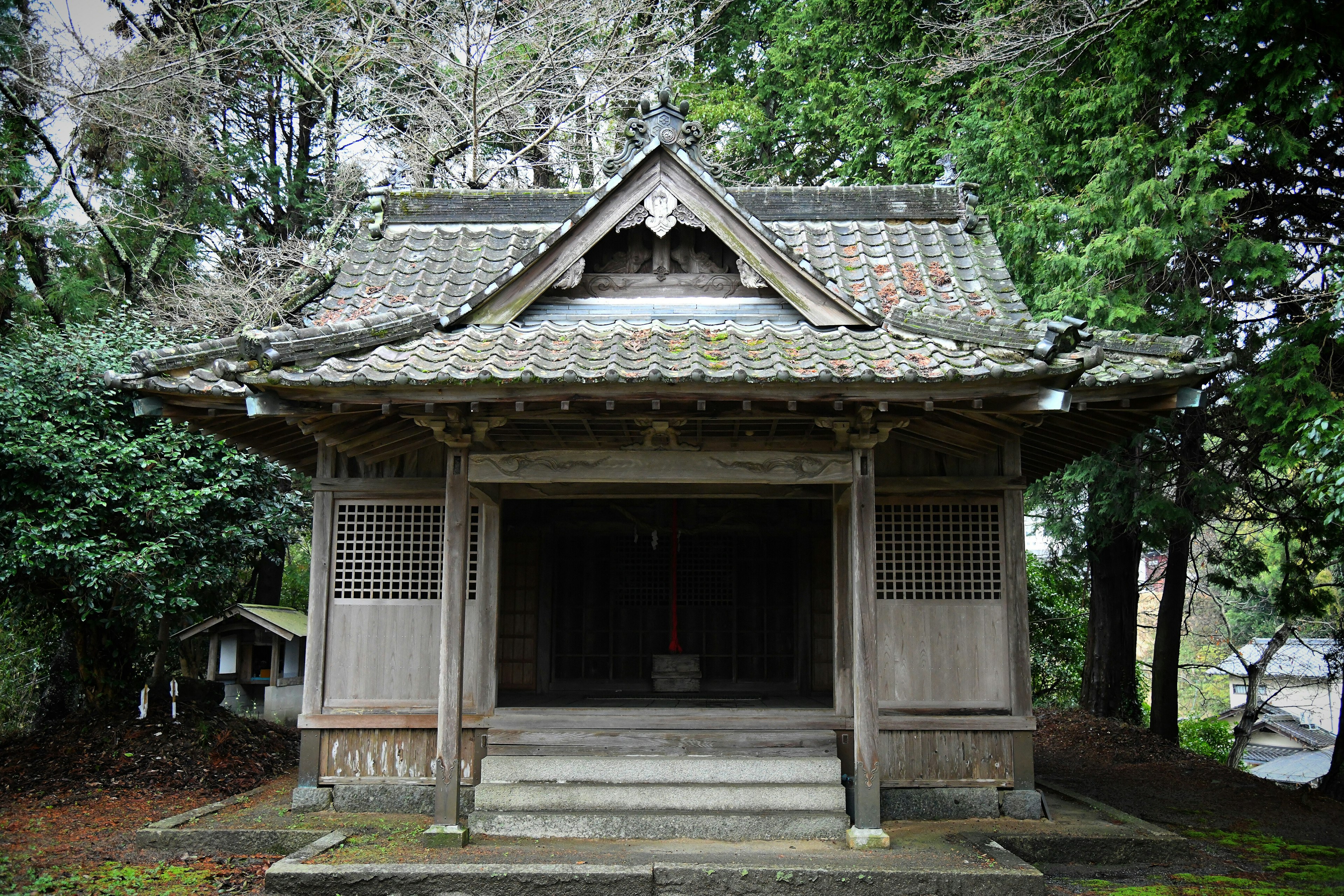 传统木制神社建筑被绿色植物包围，环境宁静