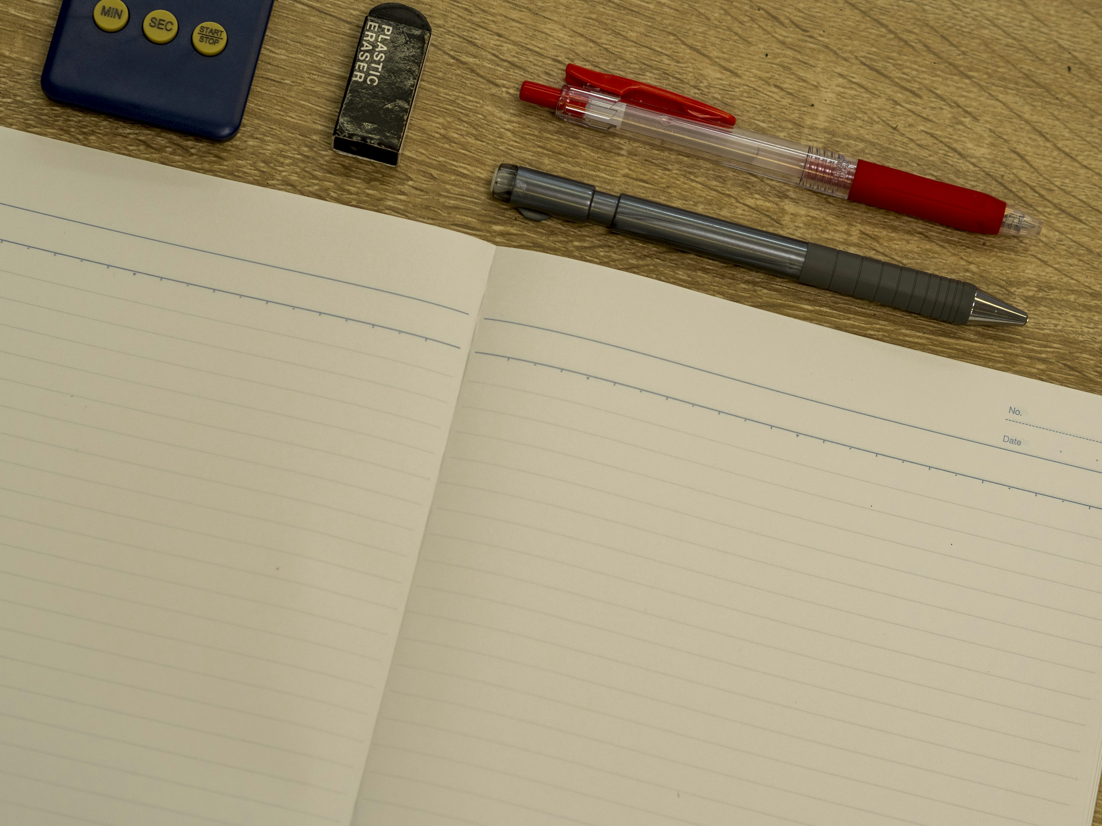 Cahier vierge avec stylo rouge stylo gris clé USB et télécommande sur une surface en bois