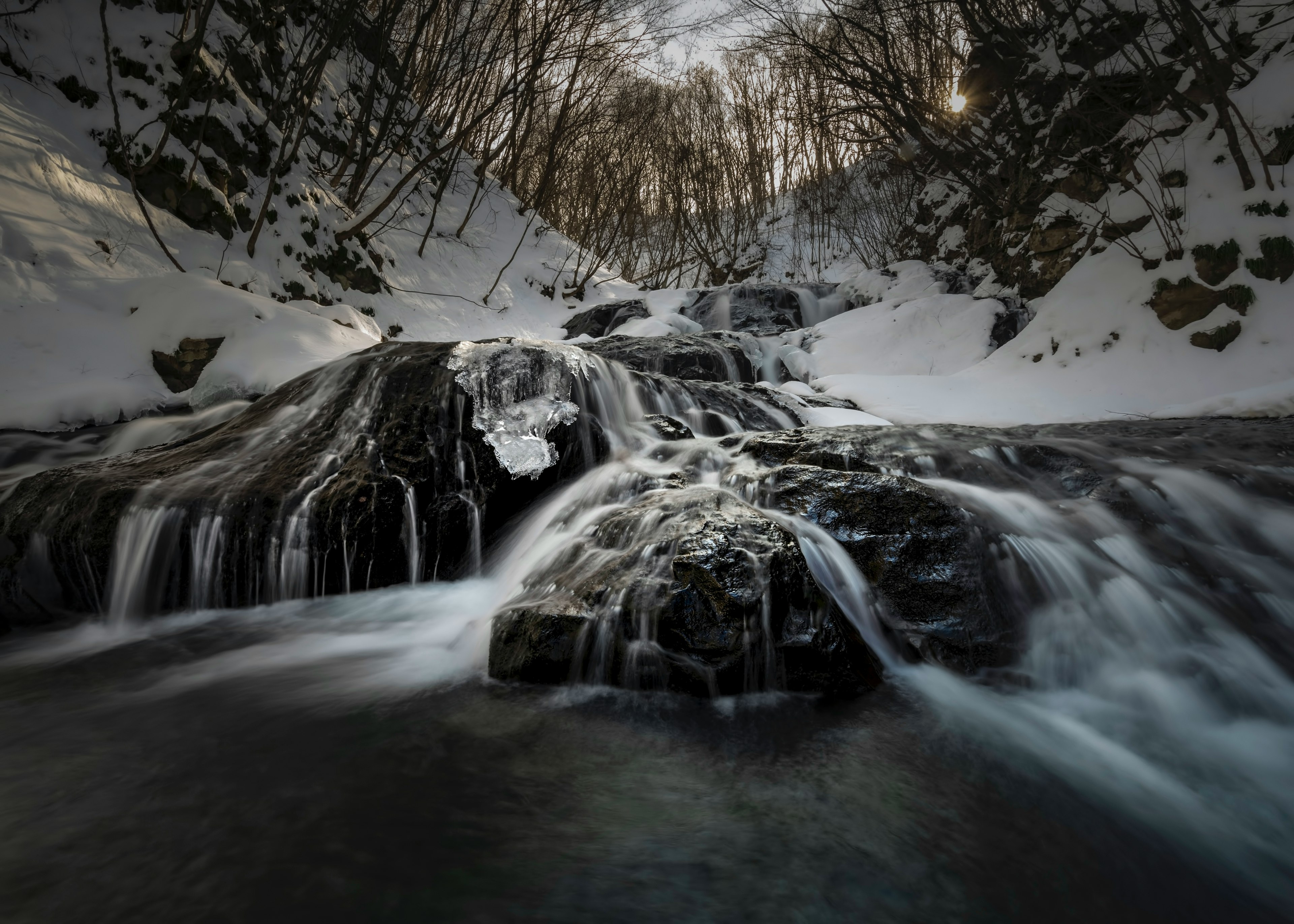 Bellissimo paesaggio di acqua che scorre su rocce coperte di neve