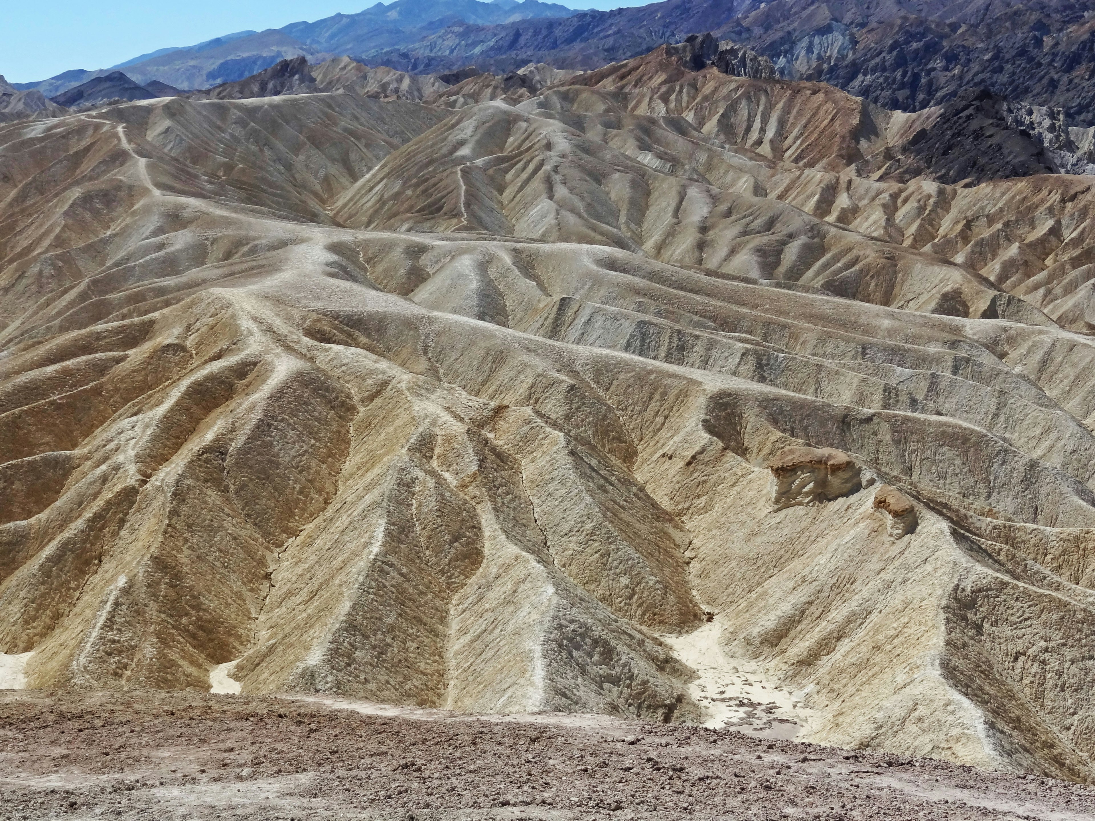 Lanskap kering dengan formasi geologi berlapis di Death Valley