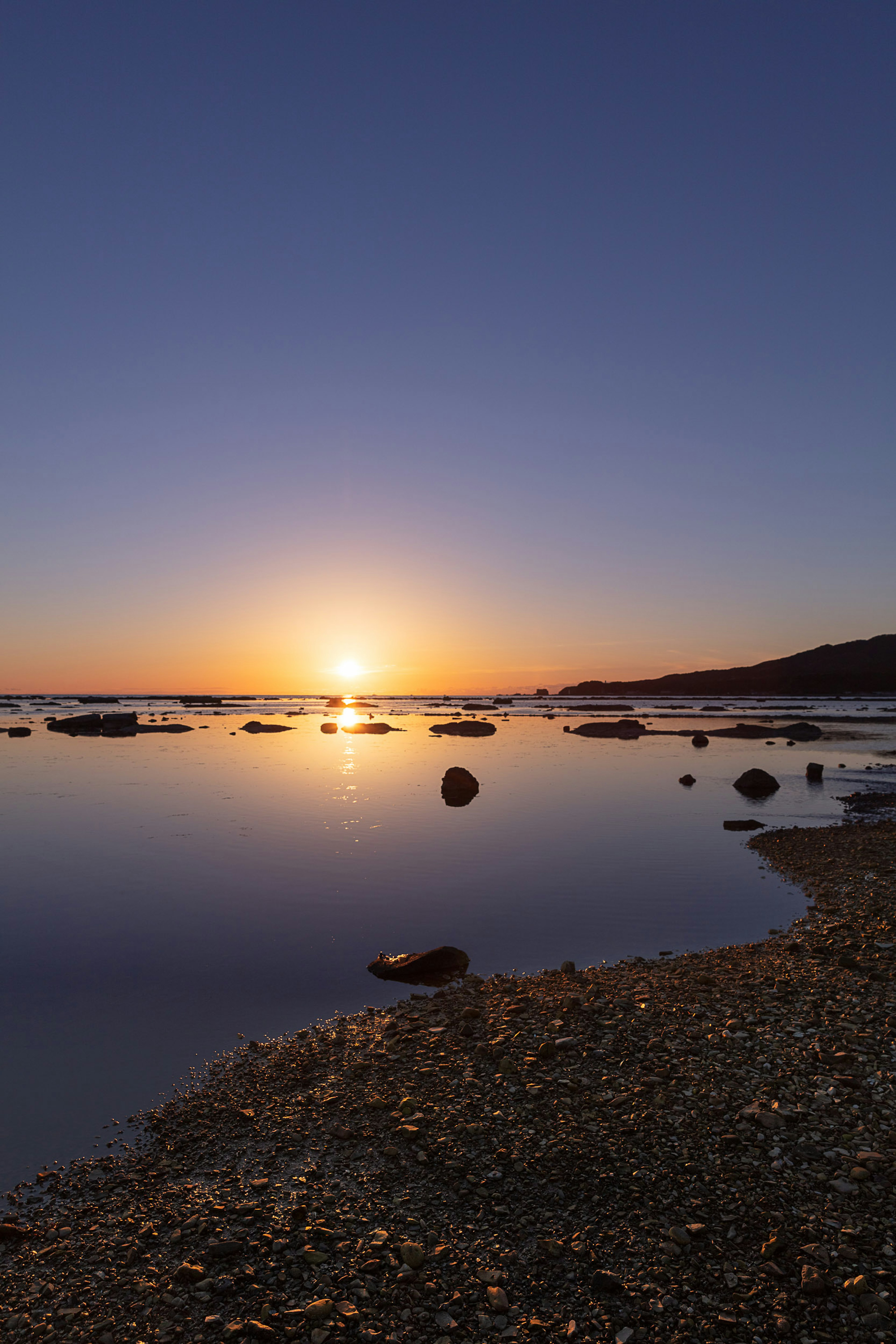 Schöner Sonnenuntergang, der sich auf ruhigen Gewässern am Ufer spiegelt