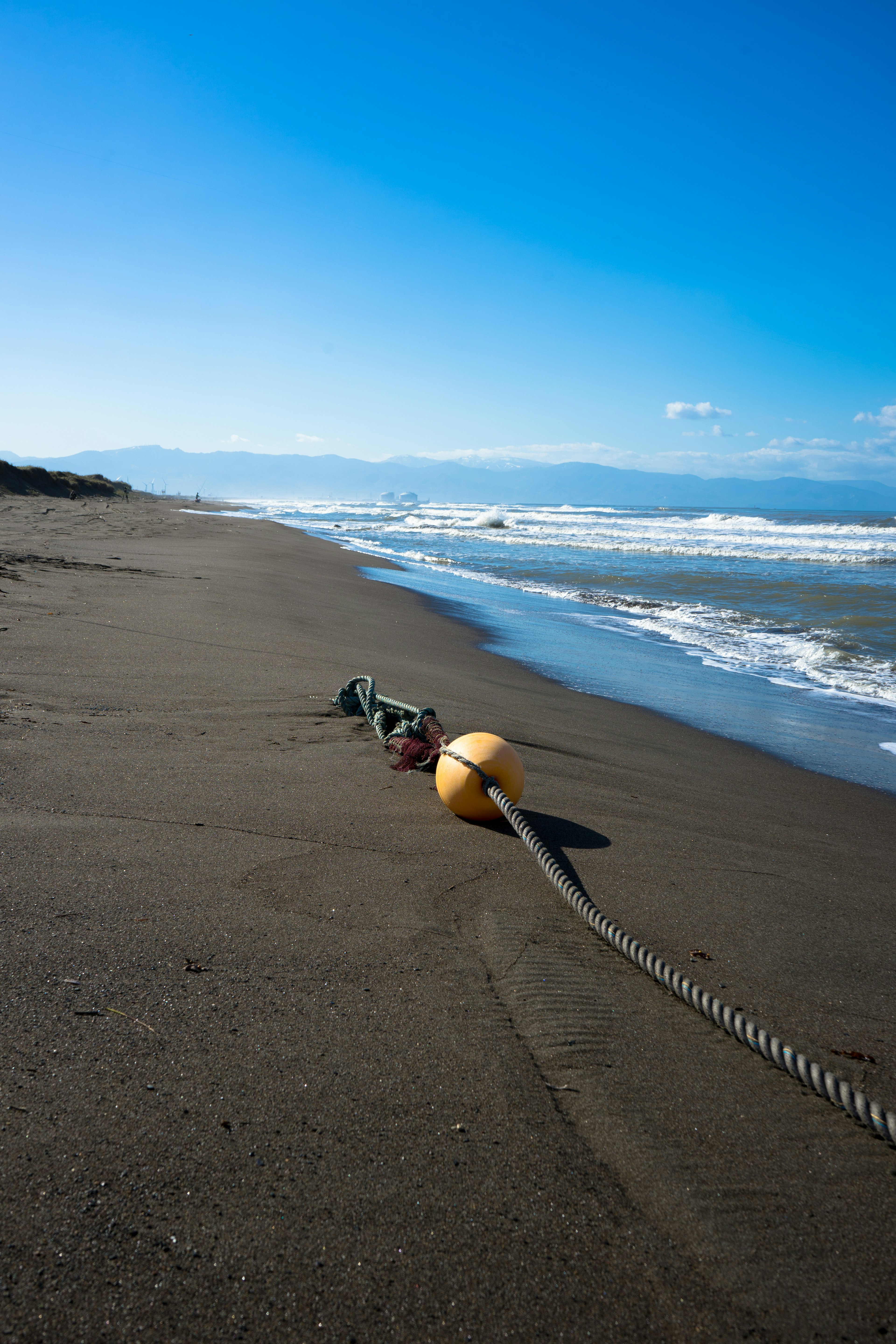 ทิวทัศน์ชายหาดที่มีบอยสีเหลืองและเชือกอยู่บนทราย