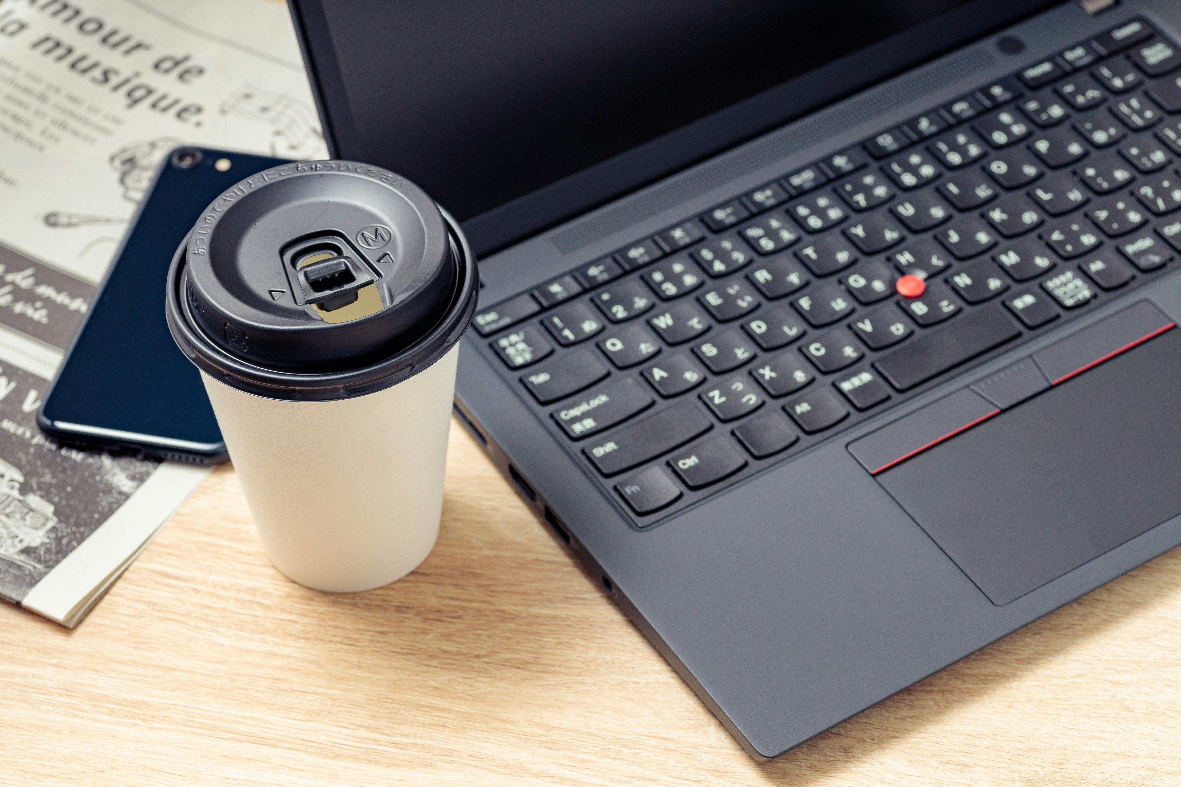 Eine Laptop-Tastatur neben einem Kaffeebecher auf einem Holztisch