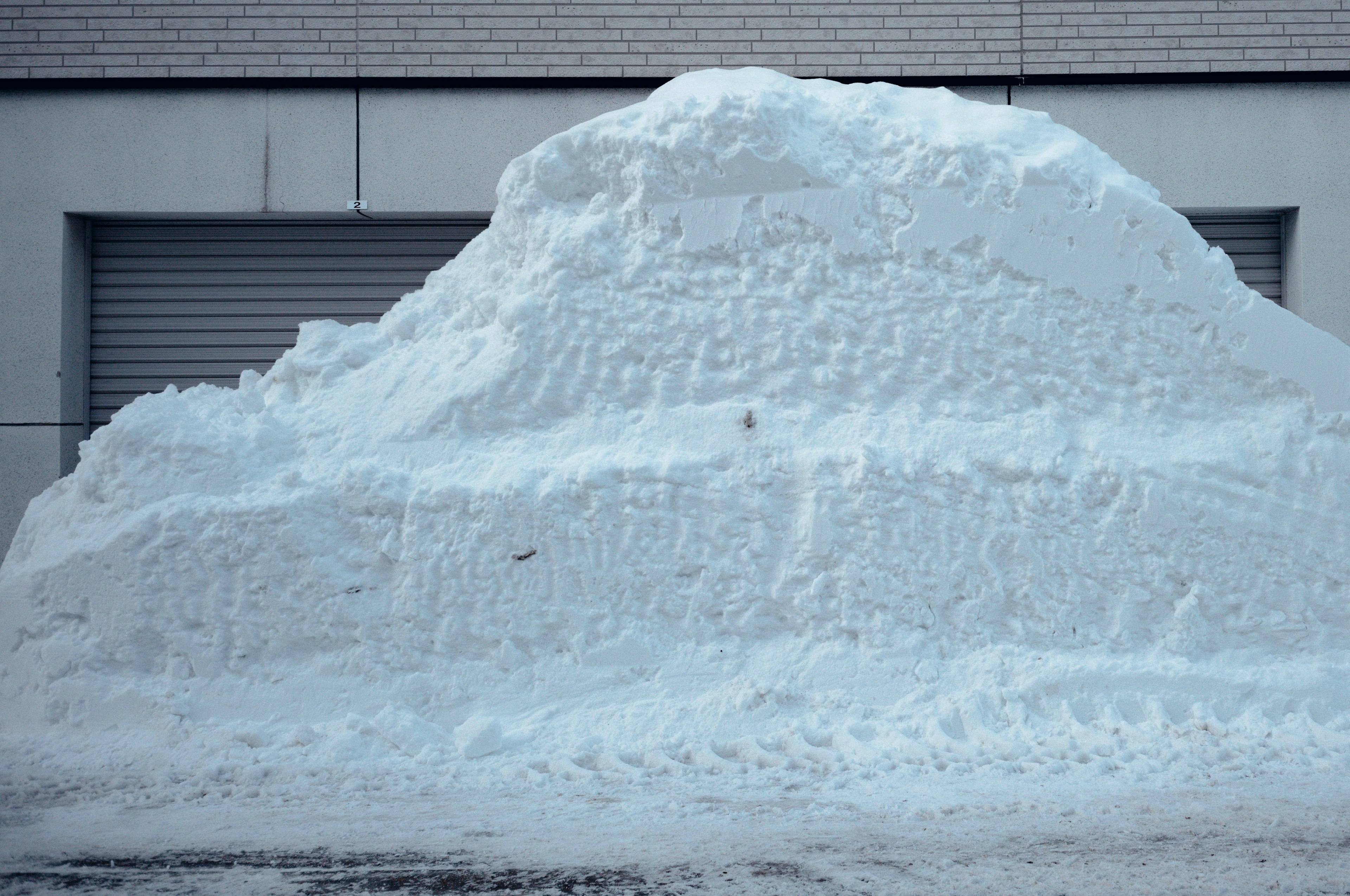 Large mound of snow against a gray wall