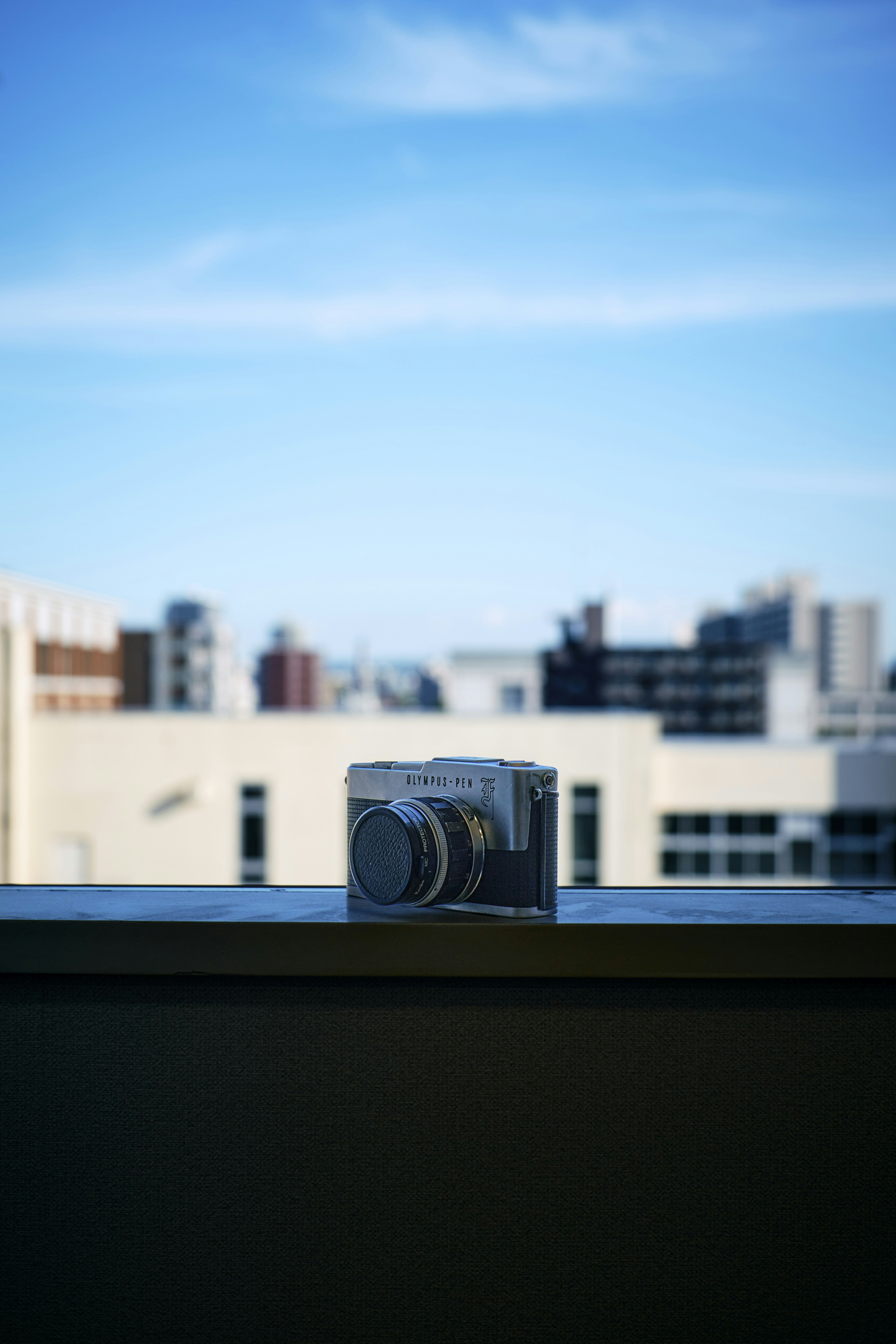 Kamera auf einer Kante mit blauem Himmel und urbanem Hintergrund