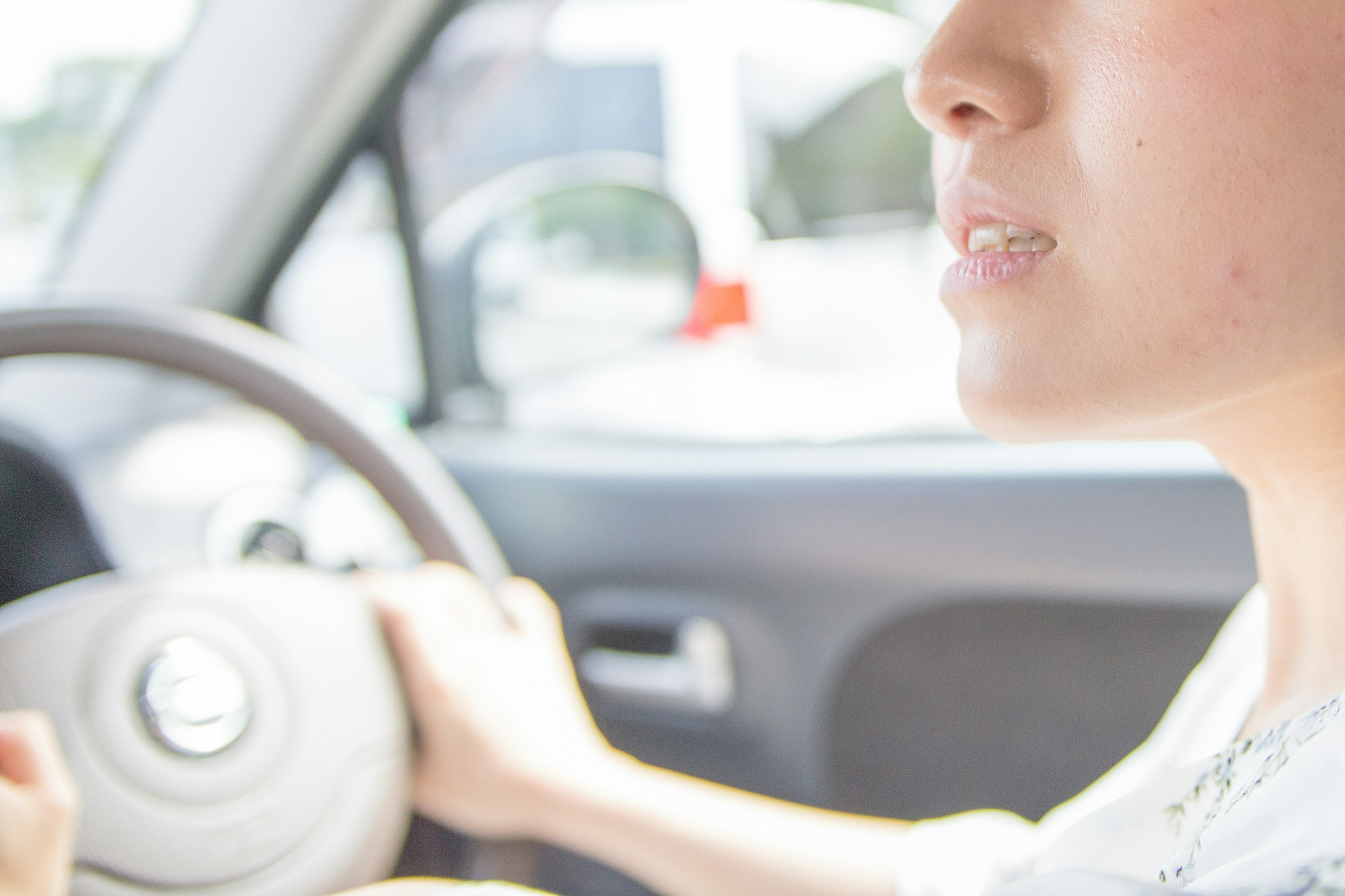 Close-up of a woman's face while driving holding the steering wheel