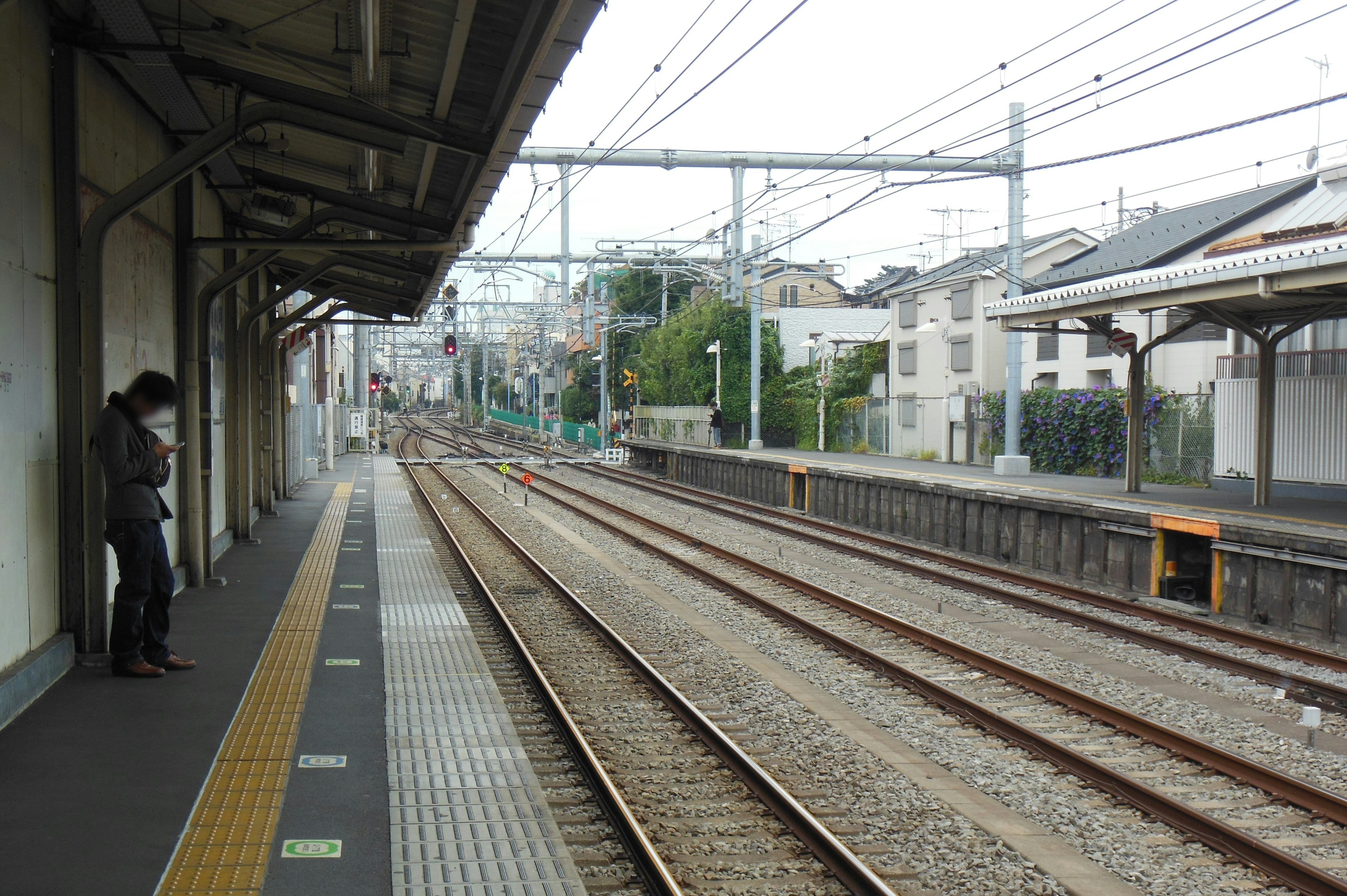 A person standing on a train platform with railway tracks