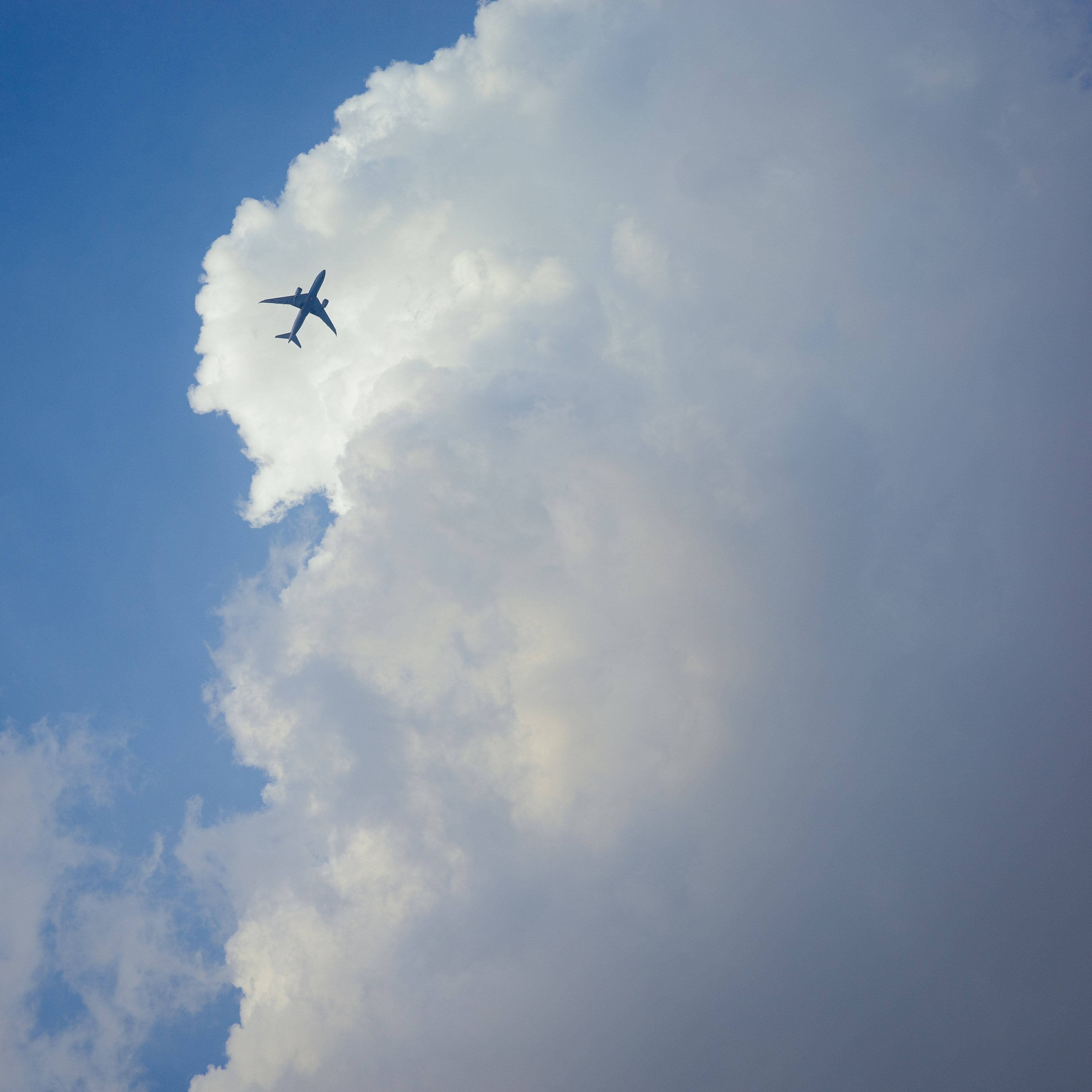 Un avión volando contra un fondo de cielo azul y nubes blancas