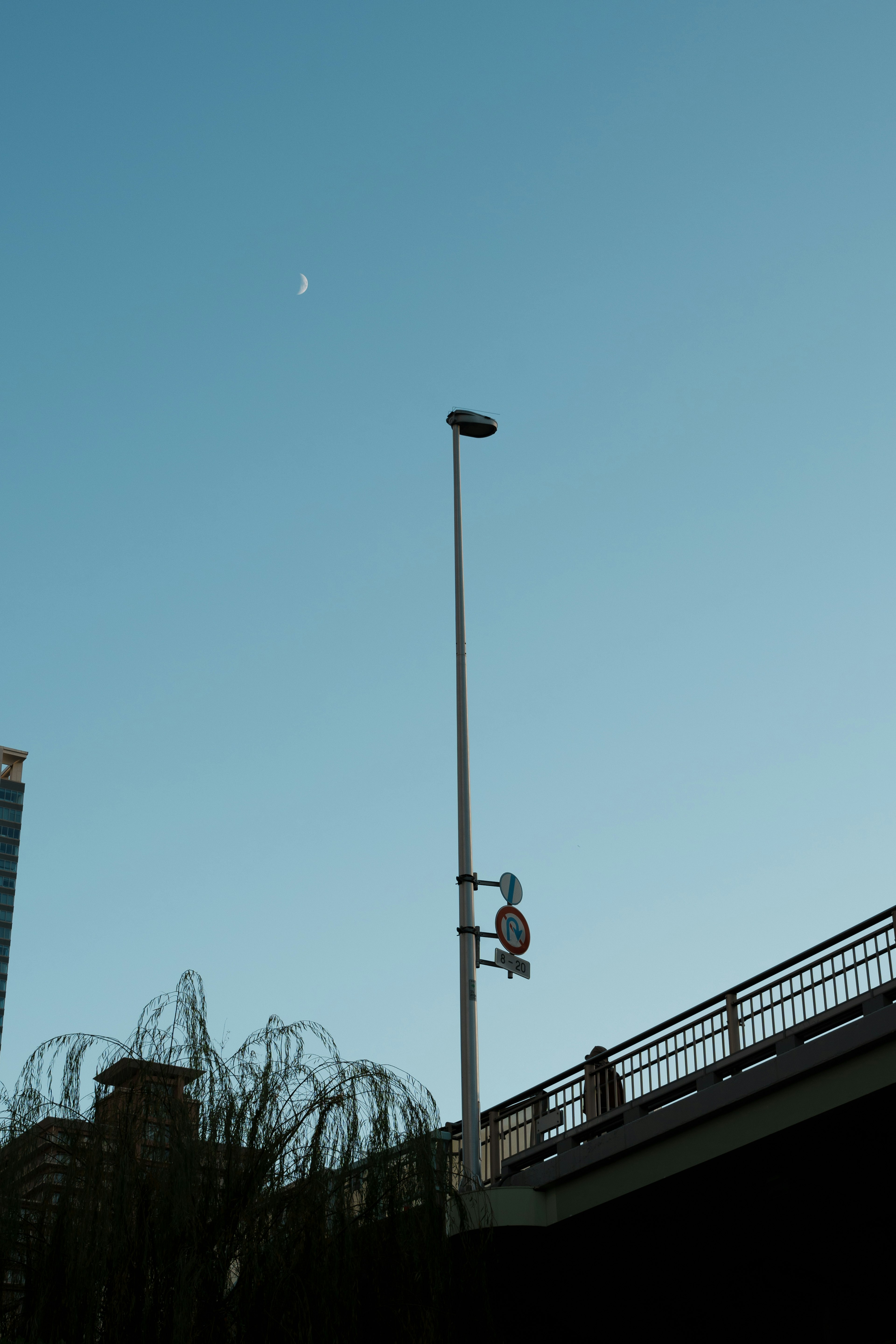 Langit cerah dengan tiang lampu tinggi dan siluet jembatan