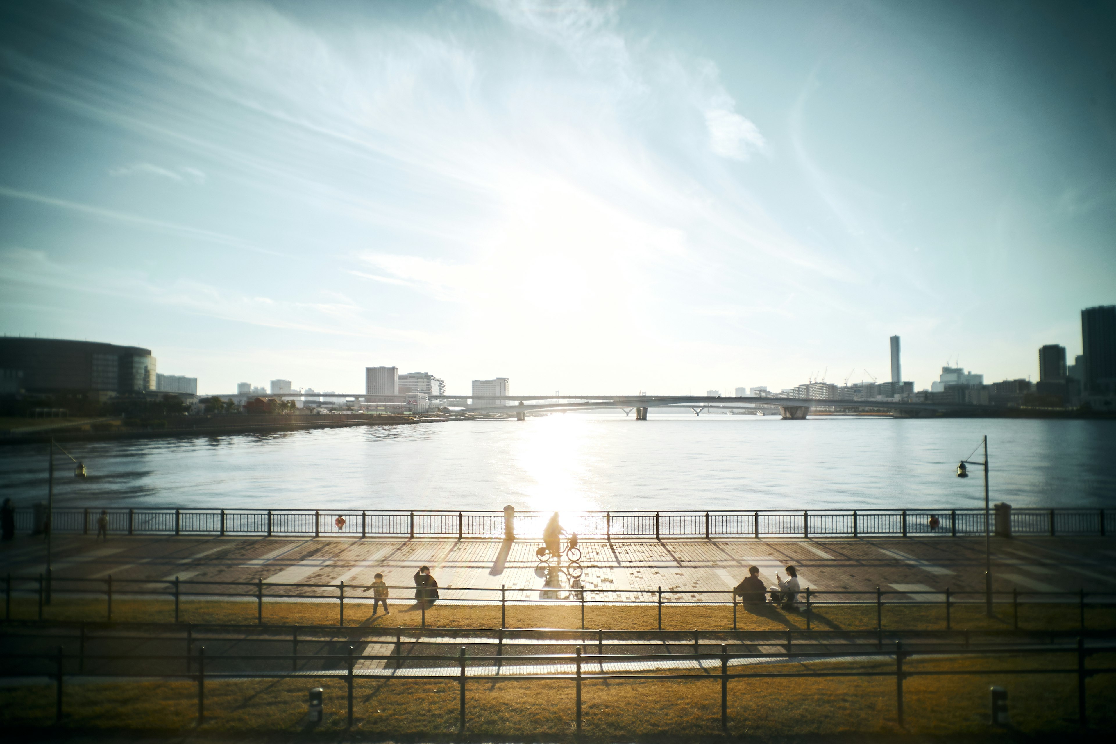 川辺の散歩道で人々が歩いている風景 鮮やかな空と水面の反射 日差しが明るい