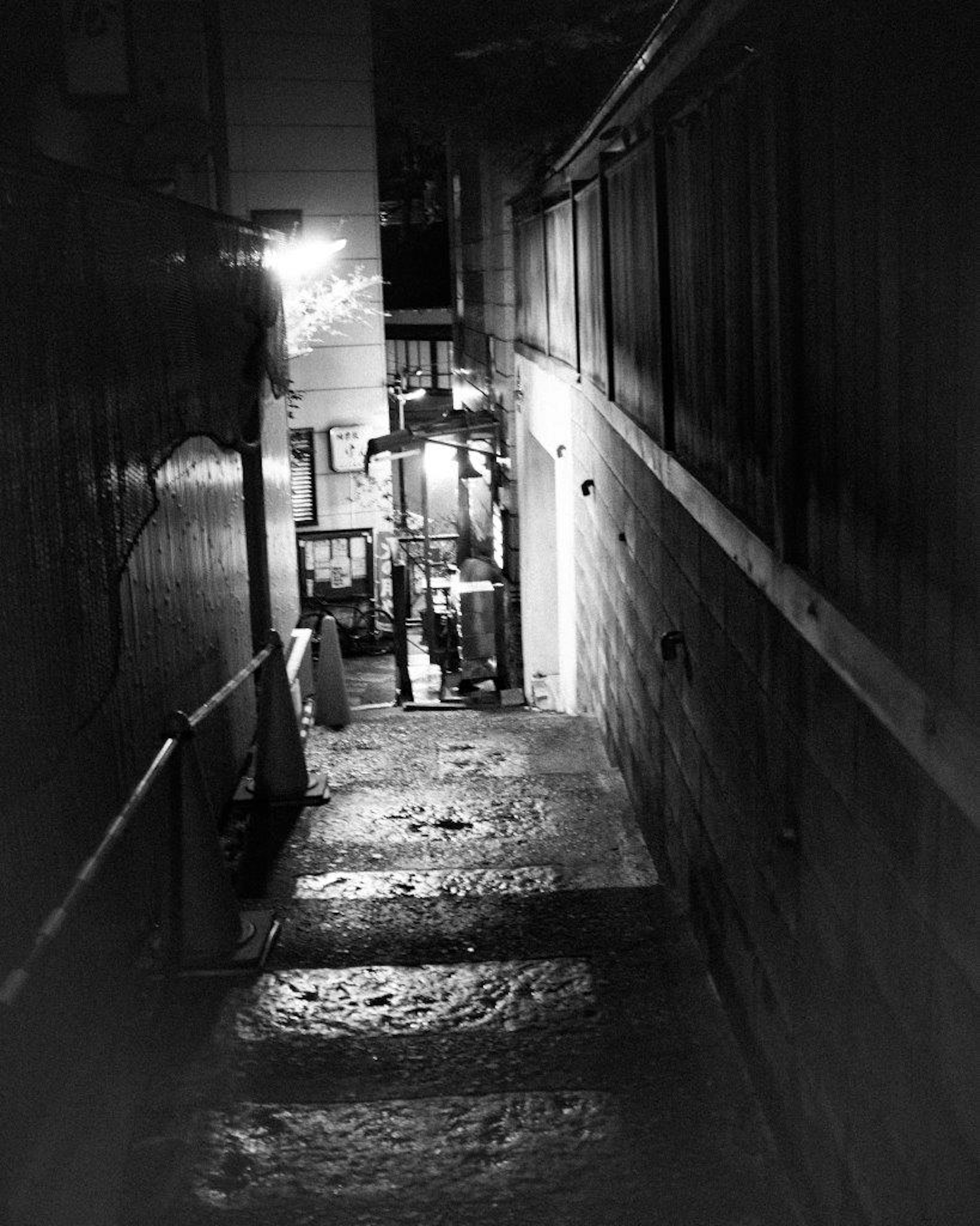 A view of stairs along a dark alley illuminated by lights