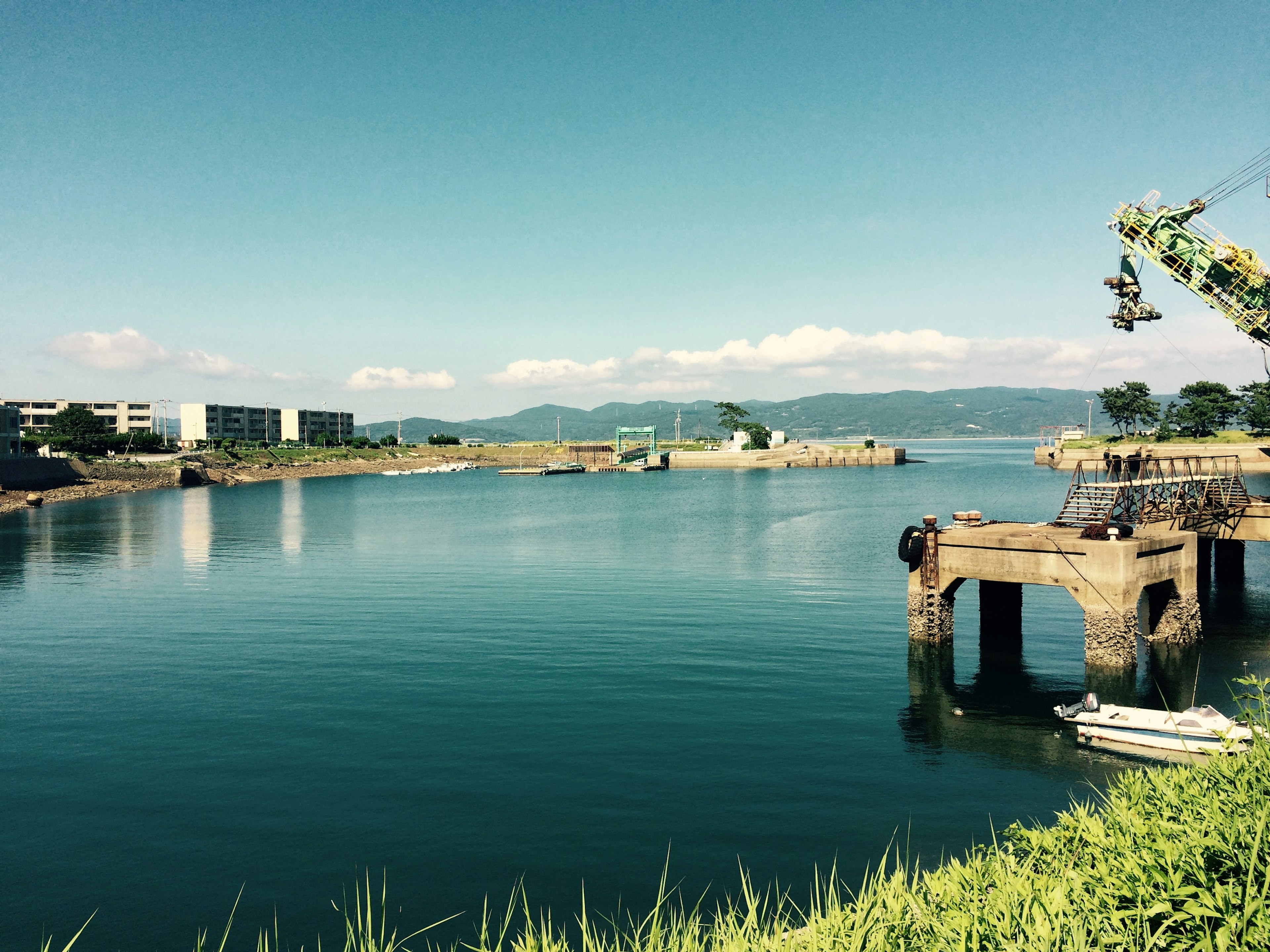 Vista escénica de agua tranquila y cielo azul con un bote y un muelle antiguo