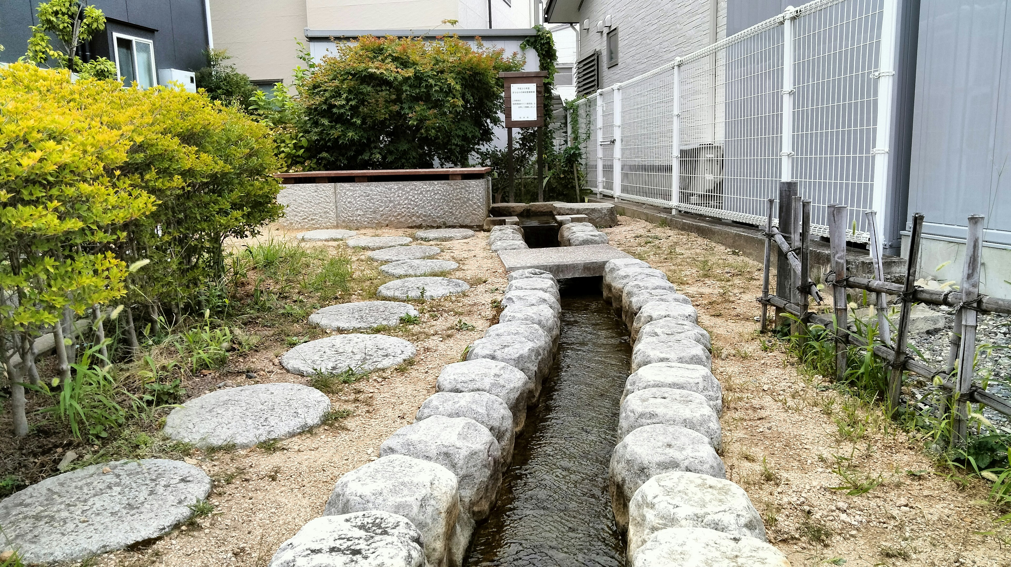 Paisaje de jardín con un camino de piedra y un pequeño arroyo