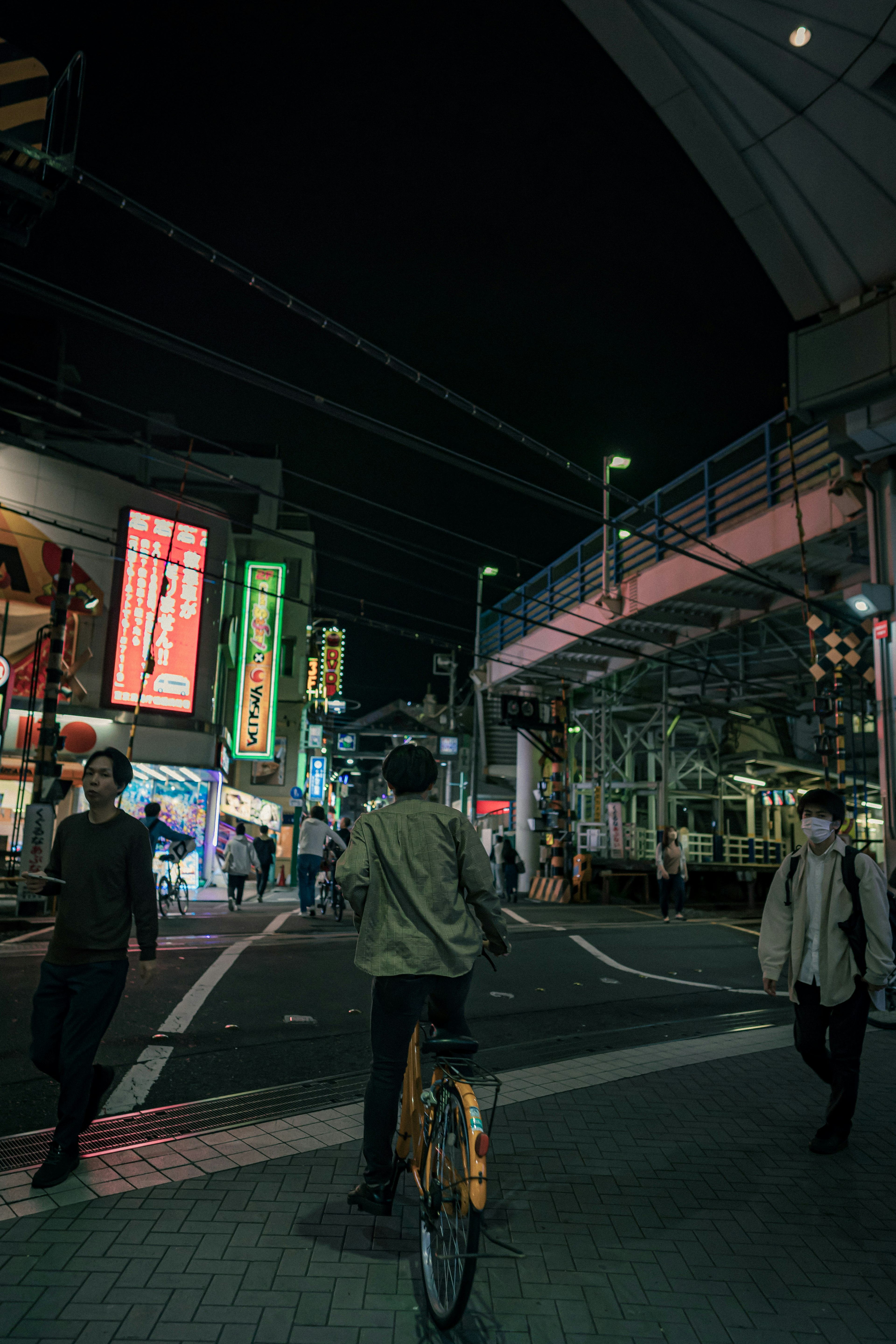 Person on a bicycle in a vibrant city street at night with pedestrians