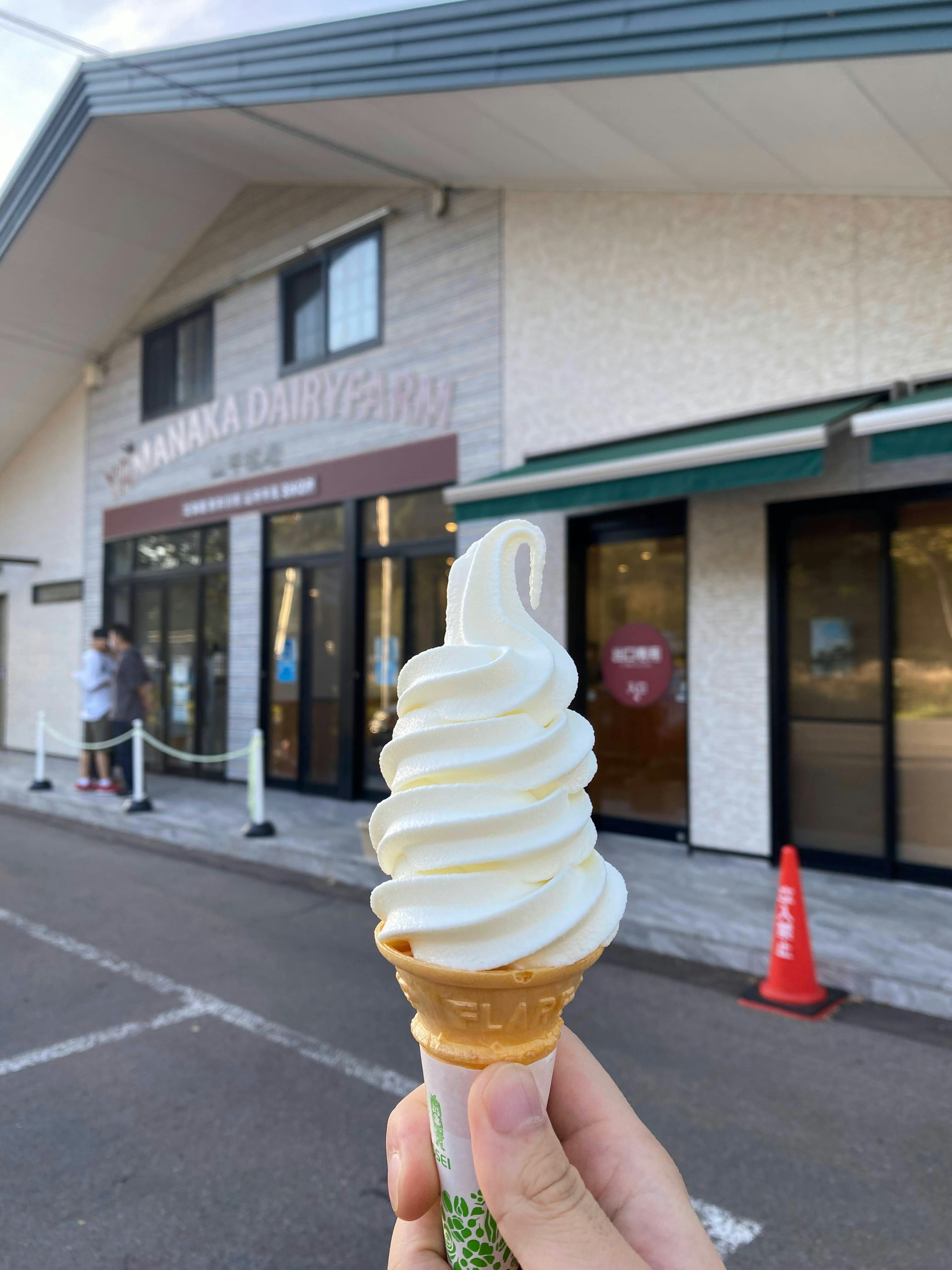 Una mano che tiene un gelato soft serve davanti a un negozio