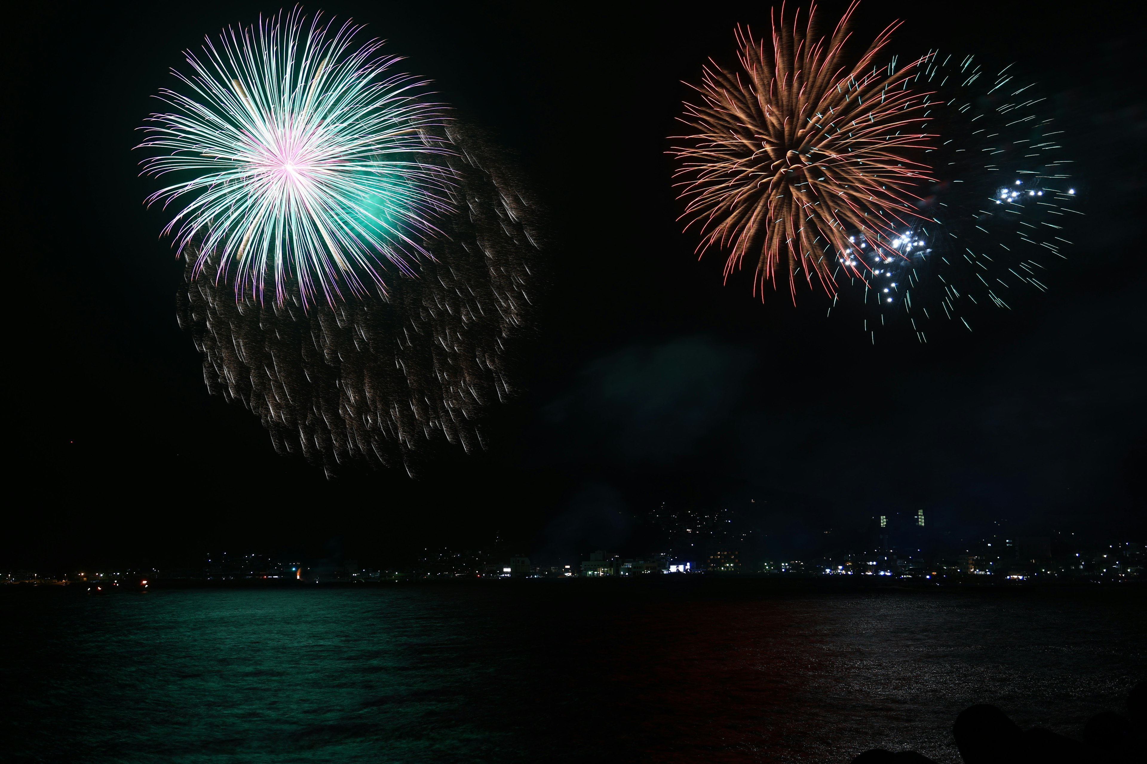 Fuochi d'artificio colorati che esplodono nel cielo notturno sopra l'acqua