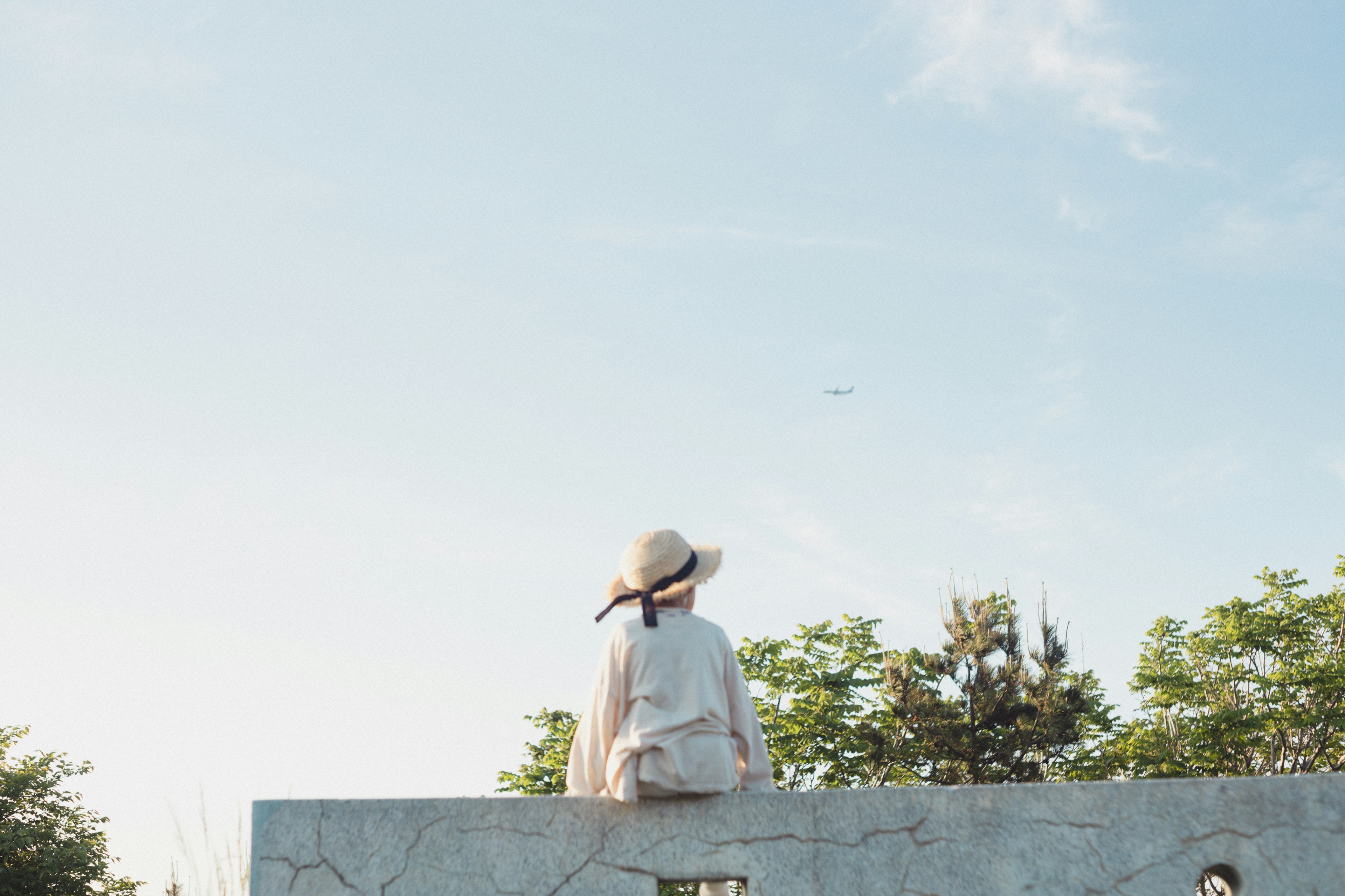 A woman sitting on a stone wall under a clear blue sky