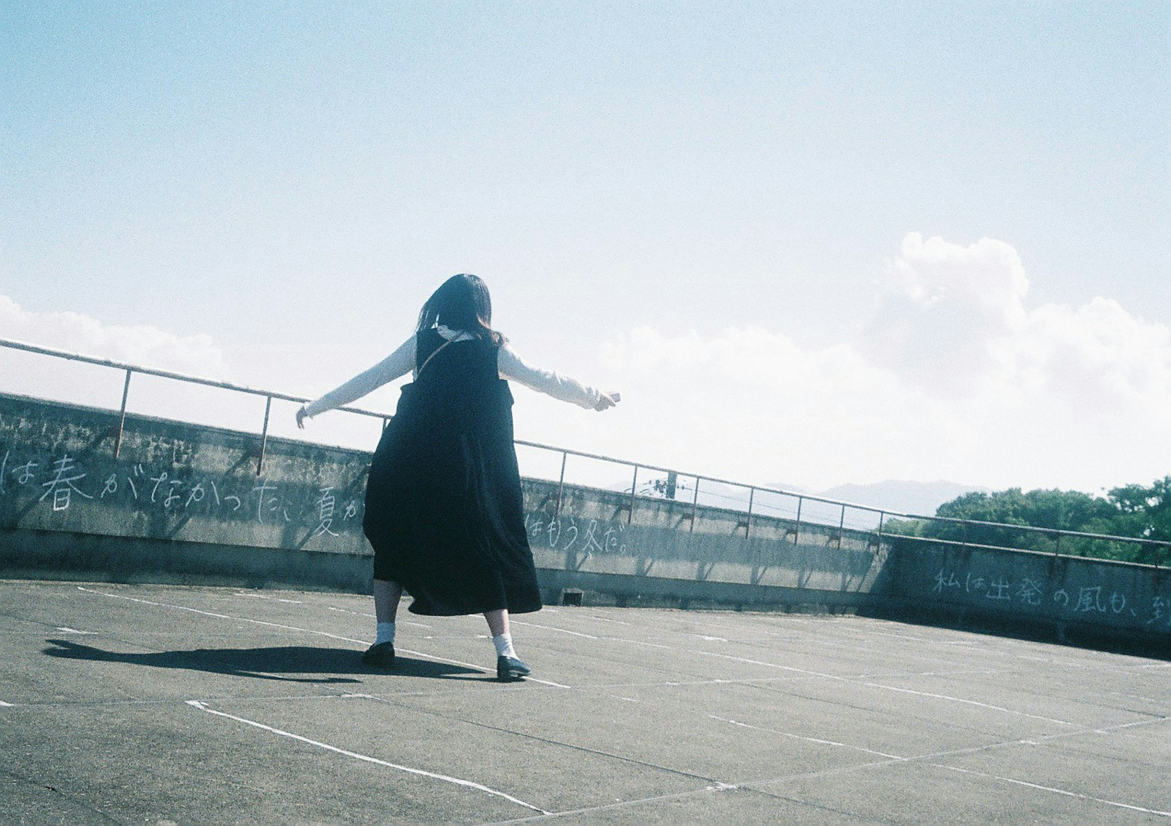 Silhouette of a woman dancing freely under a blue sky