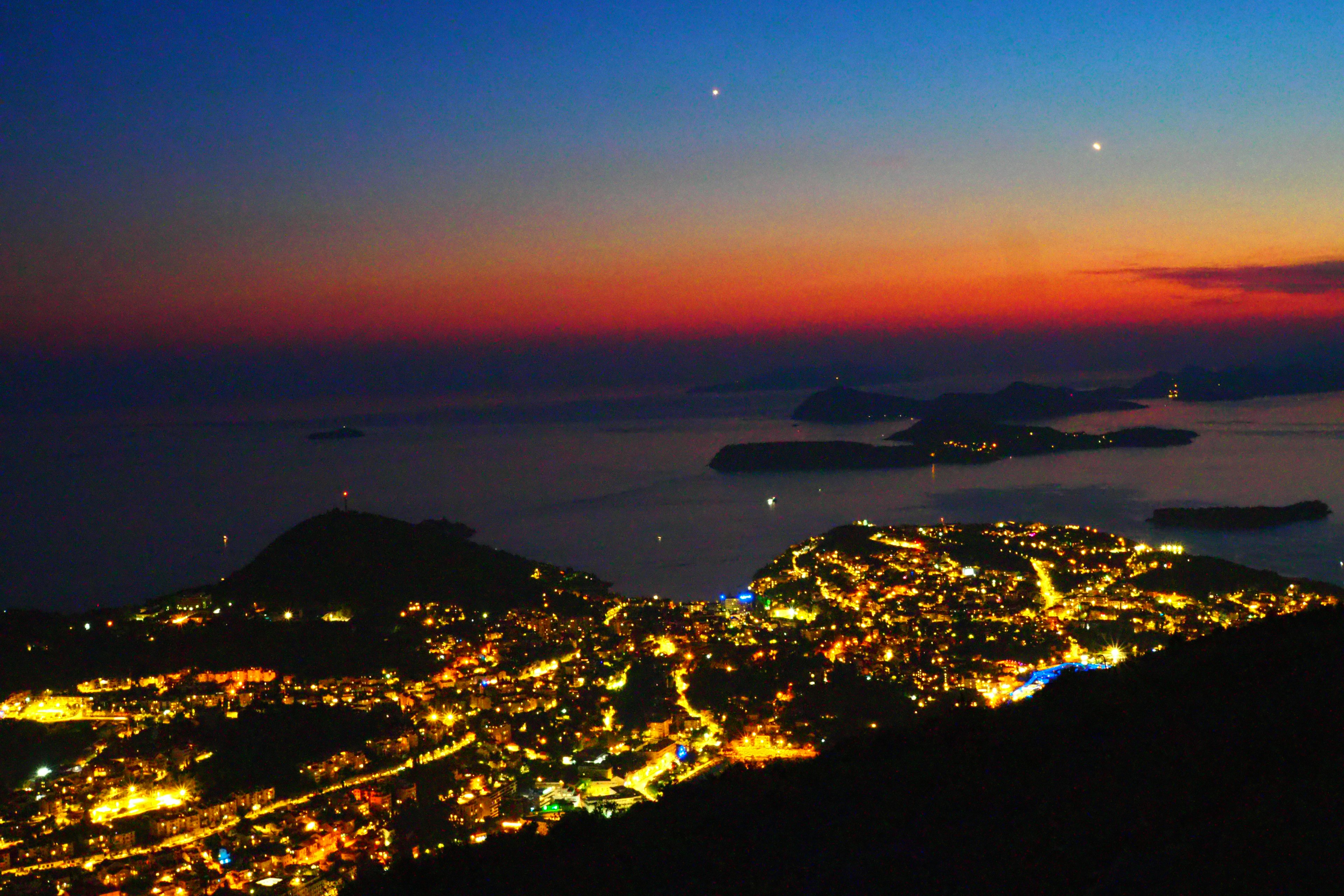 Scenic view of a sunset over the sea with illuminated city lights