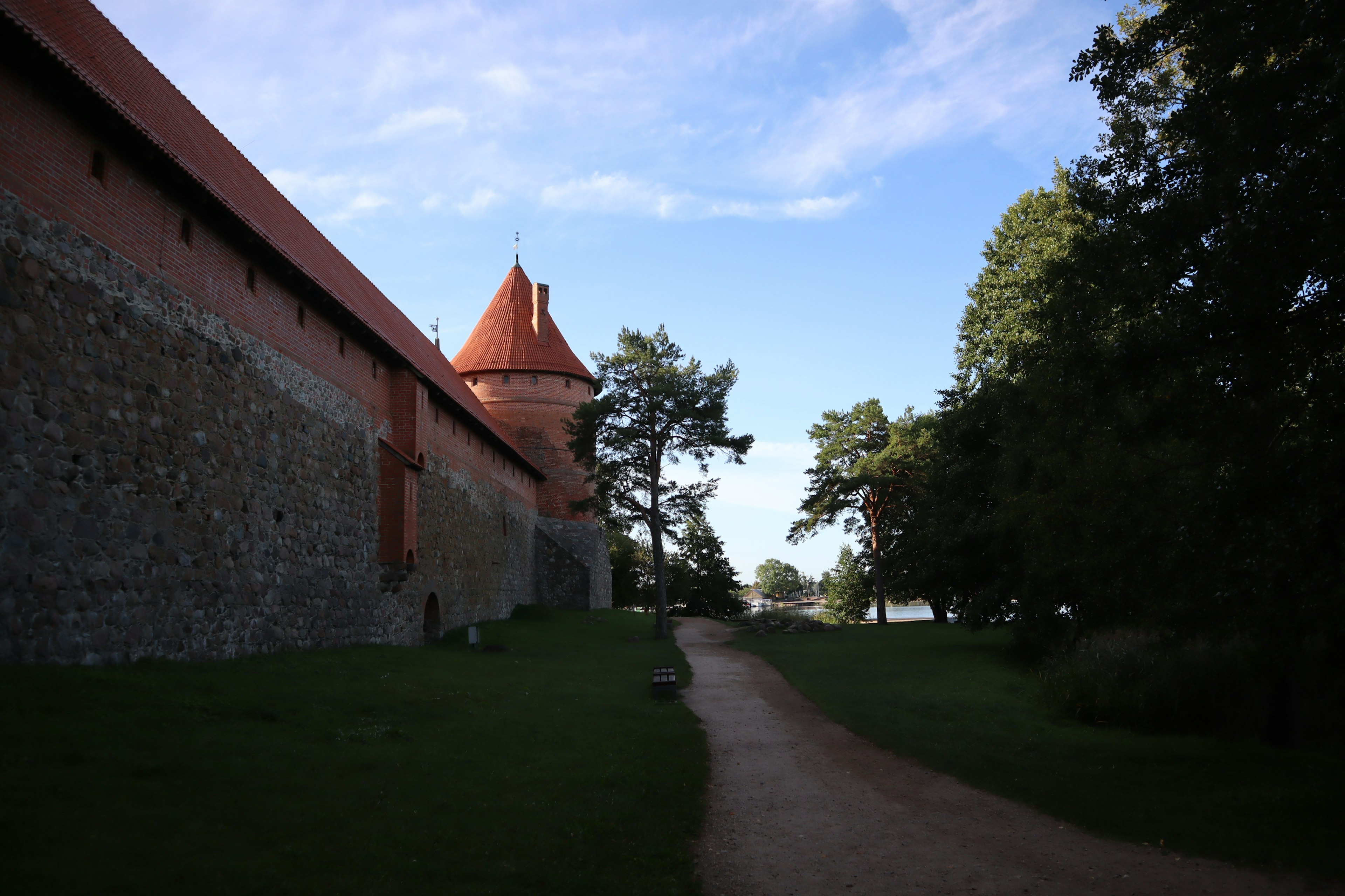 Muro de castillo de piedra con torre de techo rojo y camino verde