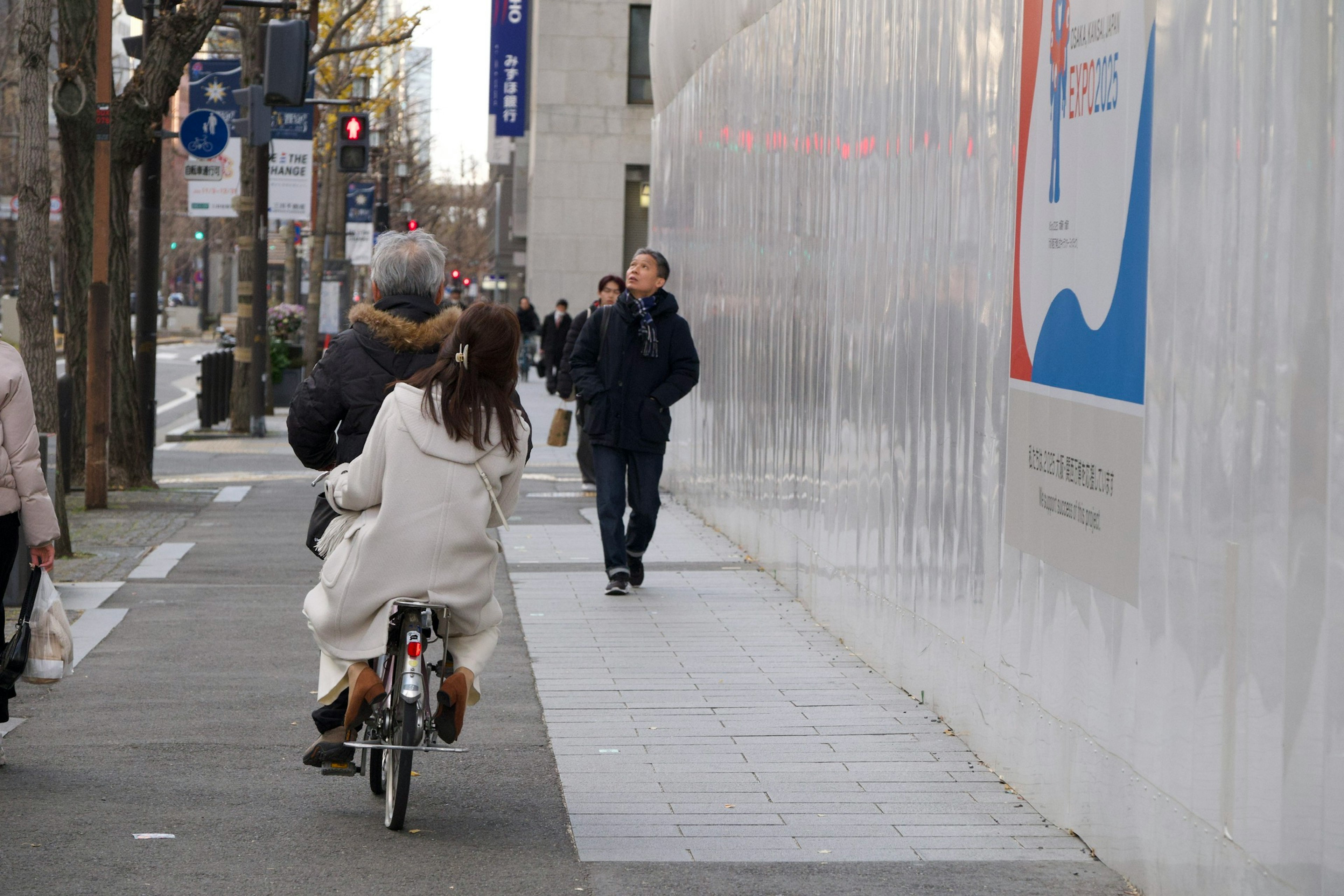 Scena di città con una donna in bicicletta e pedoni