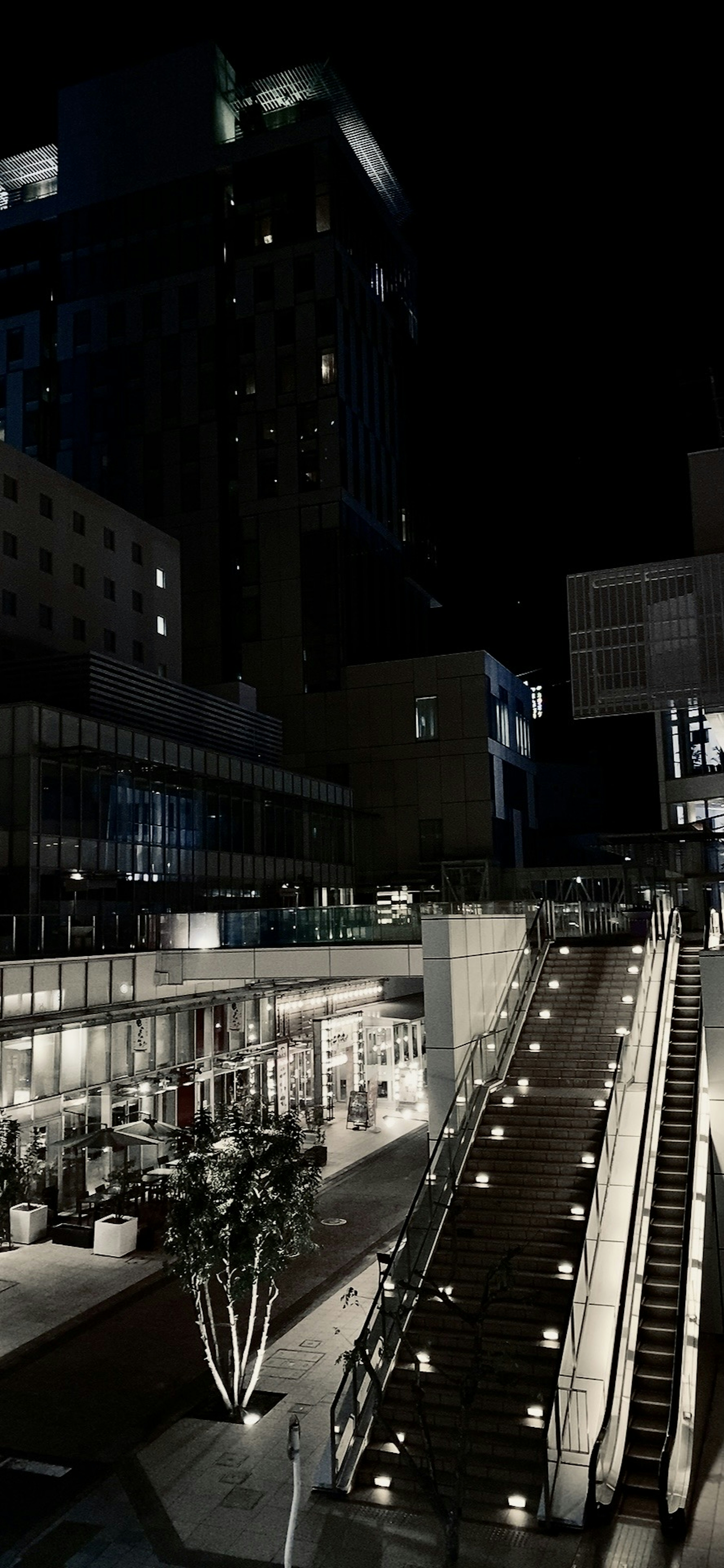 Paisaje urbano nocturno con escaleras iluminadas y edificios