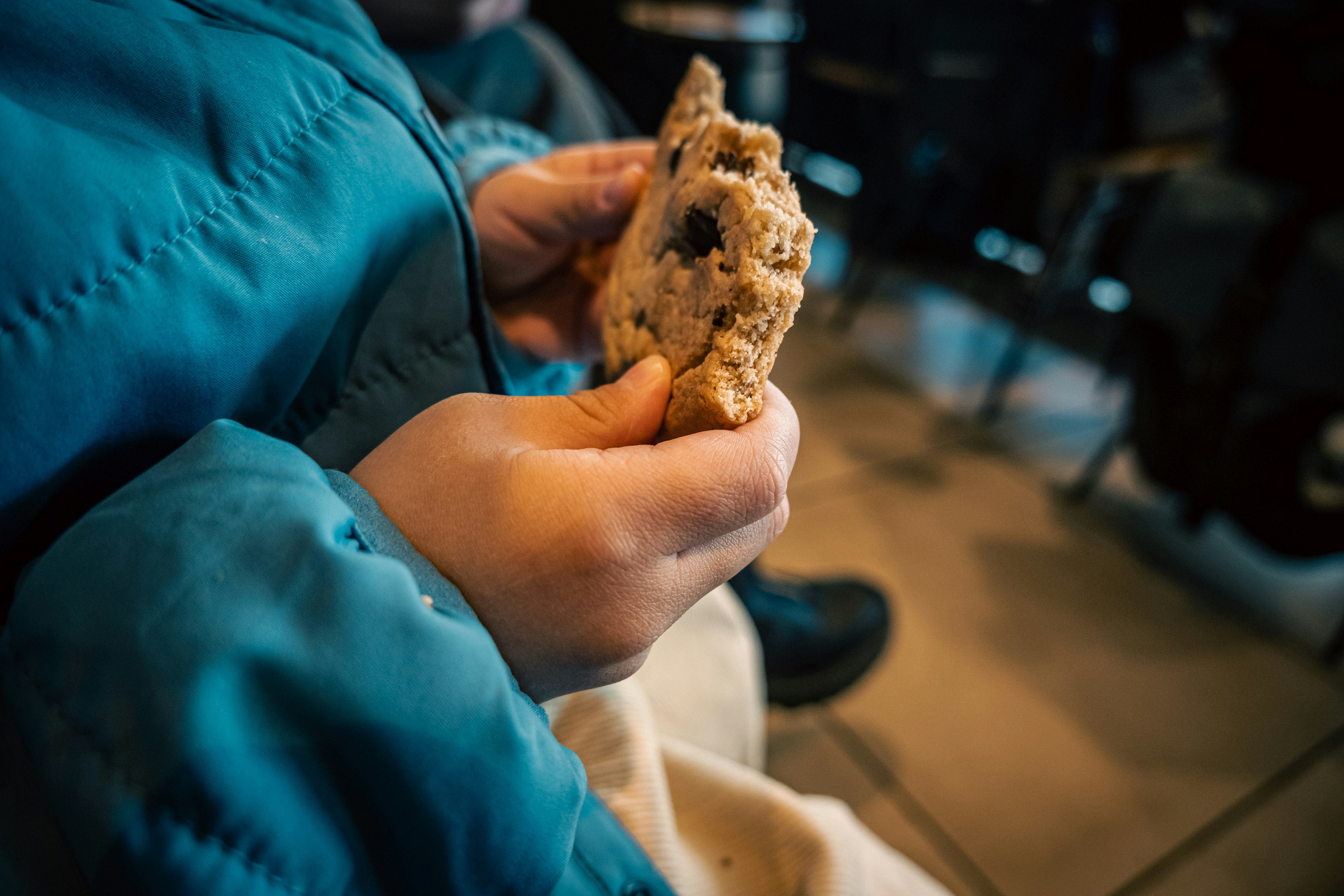 Child wearing a blue jacket holding a cookie