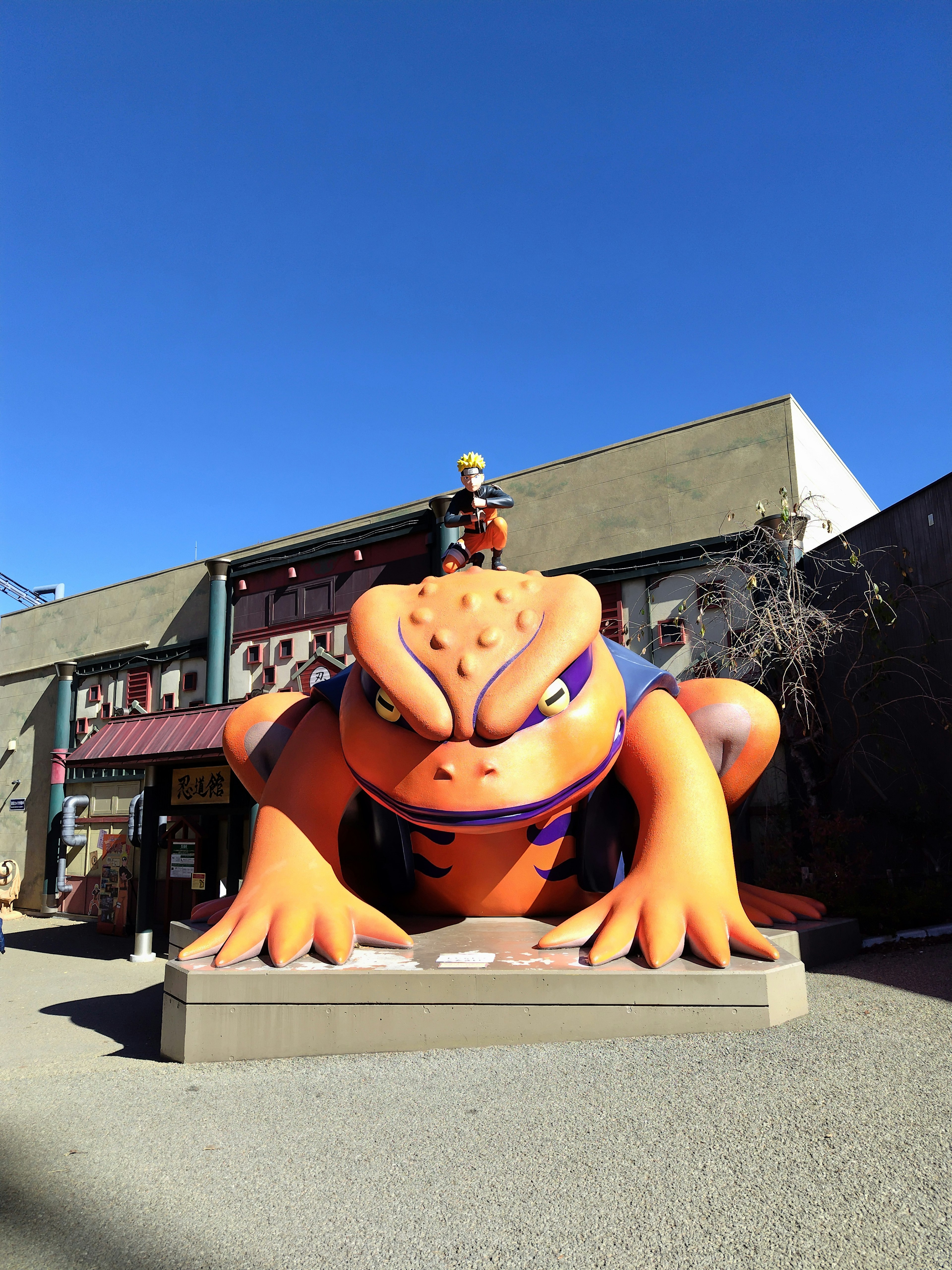 Große orangefarbene Froschfigur vor einem Geschäft