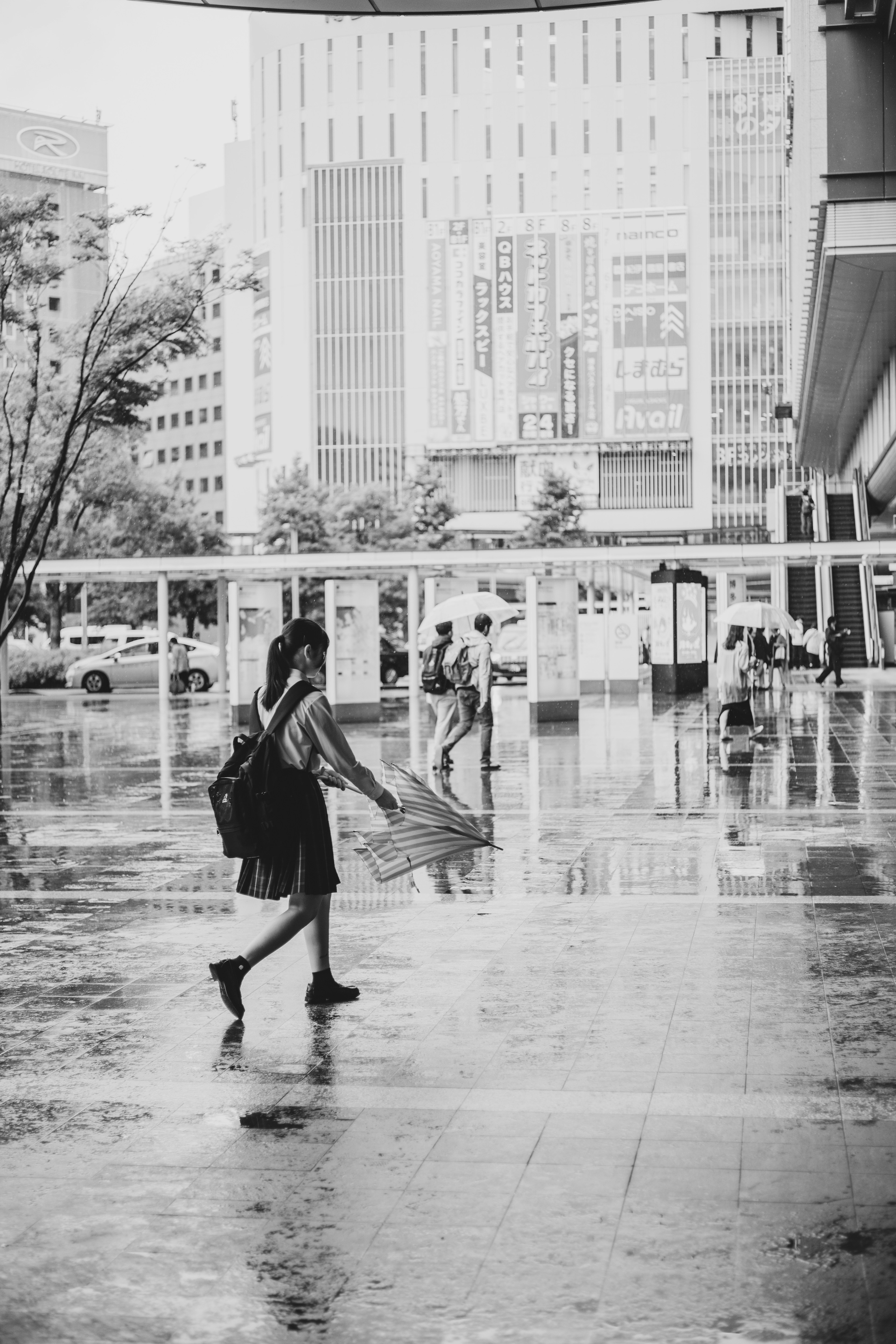 Wanita berjalan dengan payung di bawah hujan foto hitam putih latar belakang kota