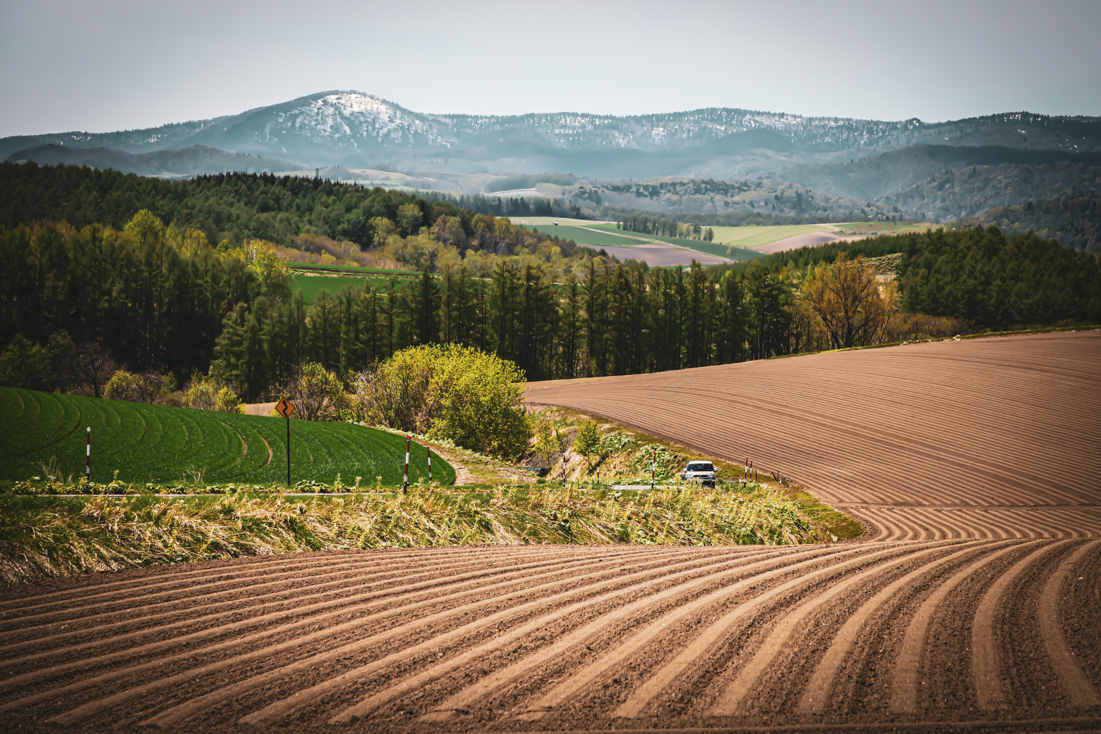 Expansive farmland with rolling hills and distant mountains featuring cultivated fields