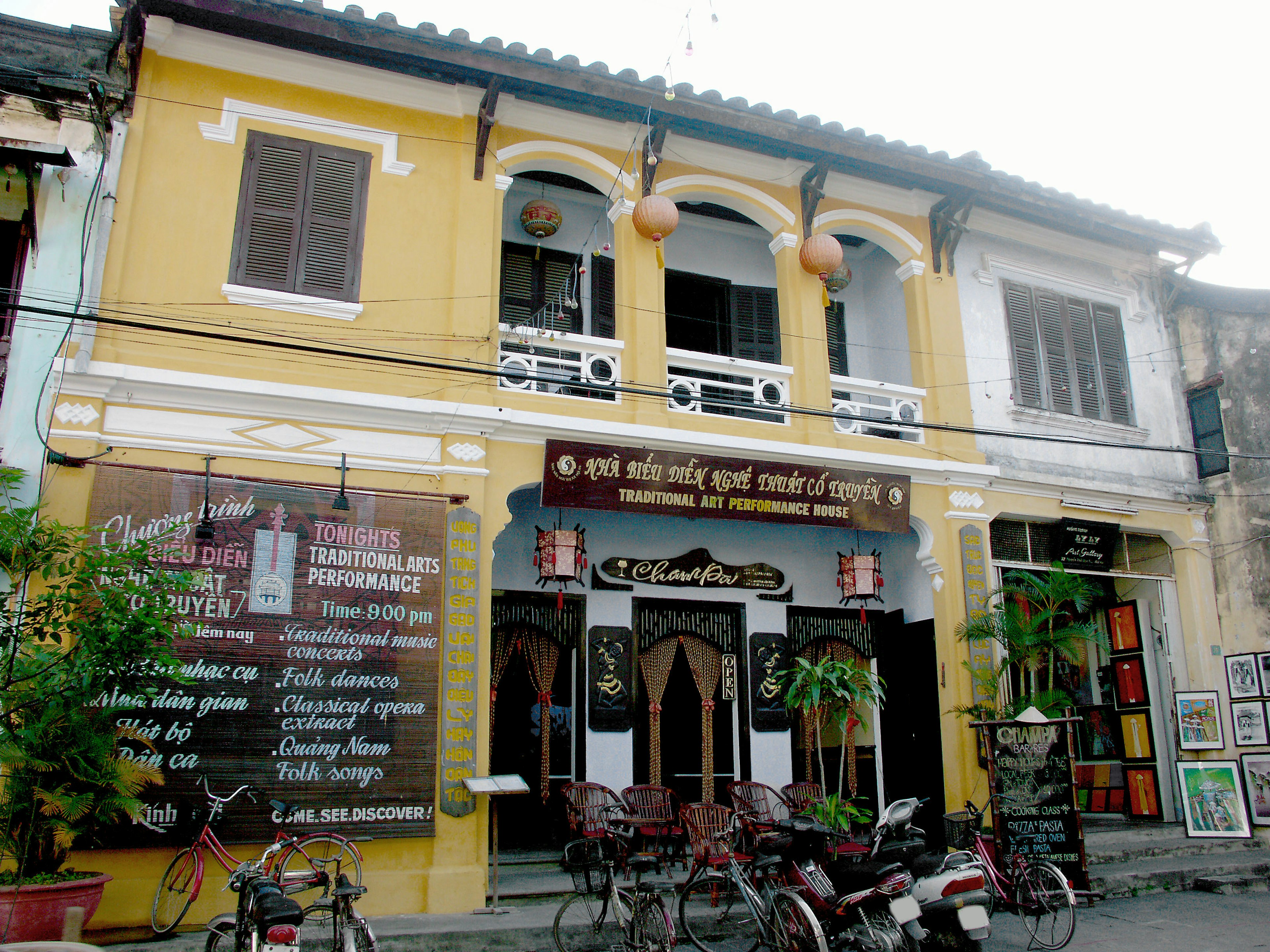 Historic building facade with yellow walls and arched windows featuring signage and greenery