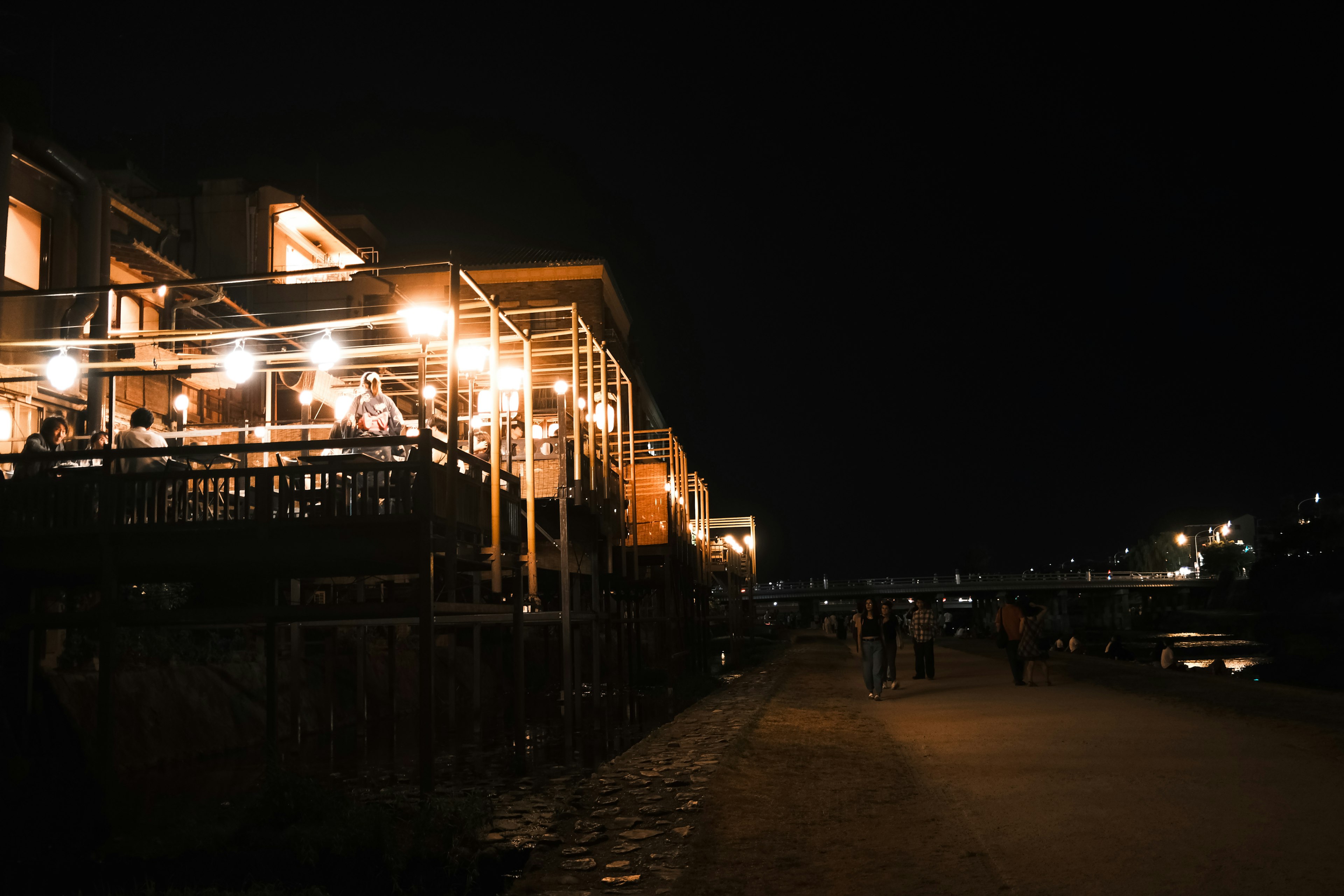 Row of illuminated restaurants along the riverside at night