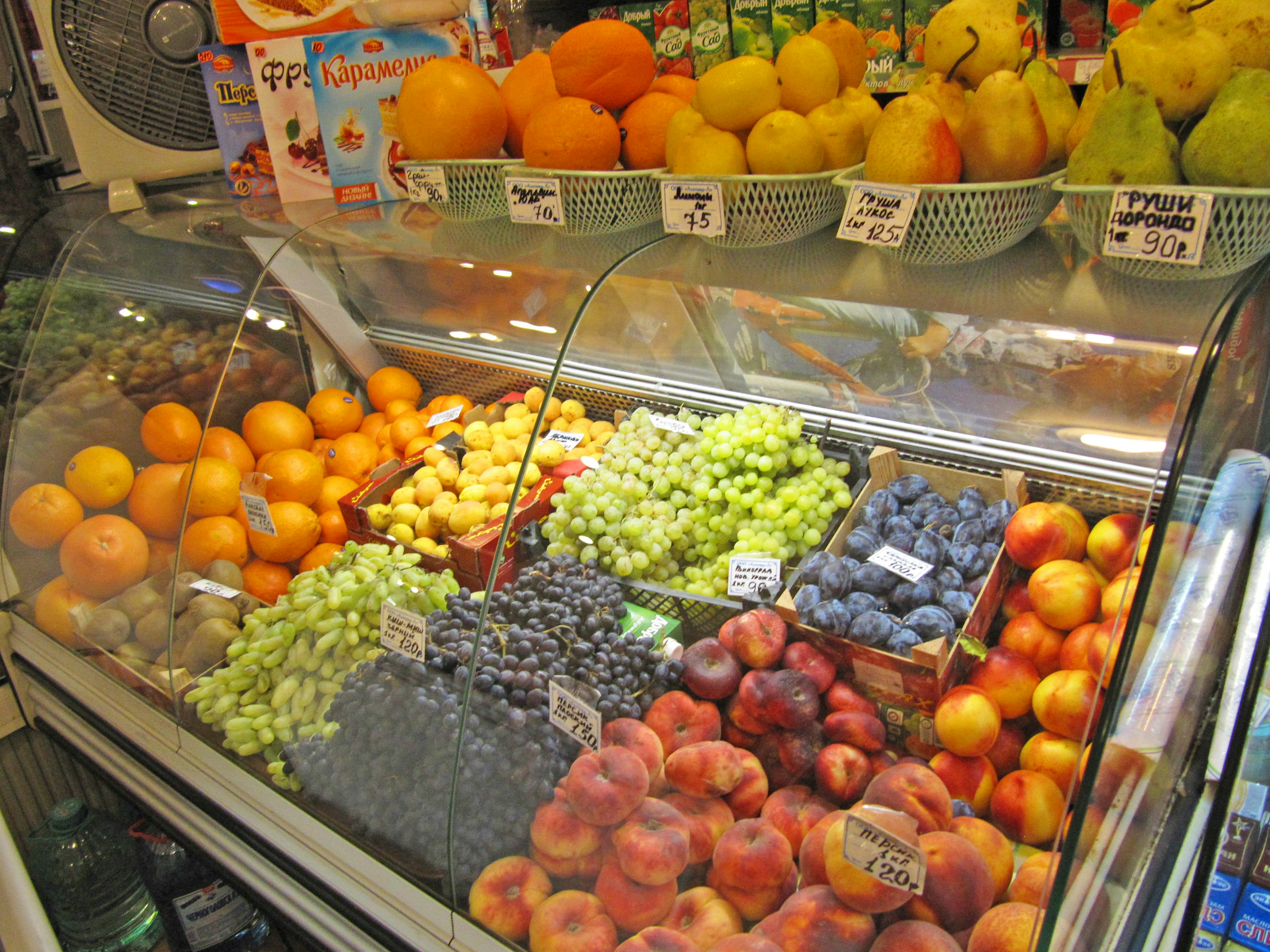 Vibrant fruit display in a market featuring oranges, grapes, blueberries, nectarines, and apples