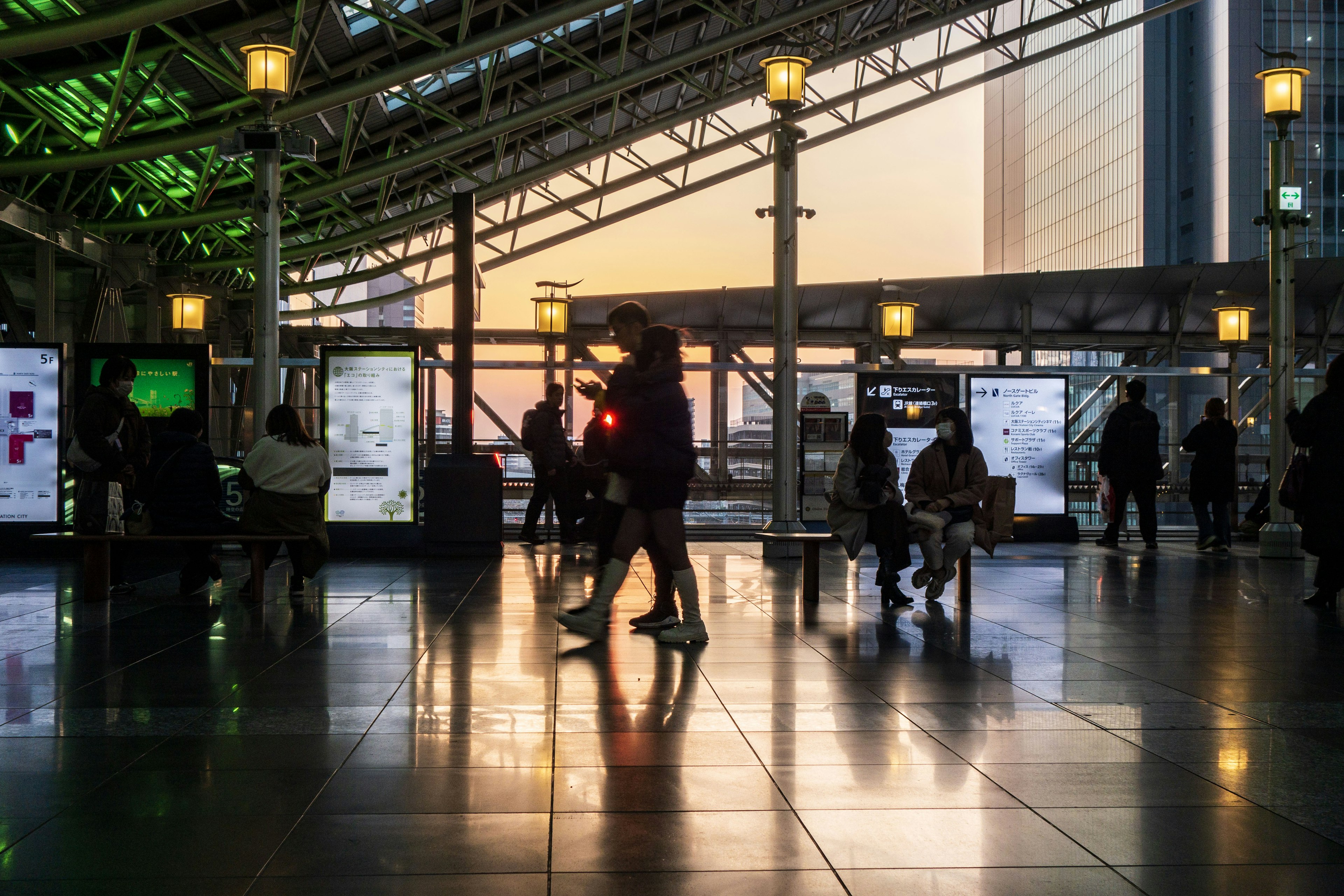 Interior view of a station with people walking during sunset