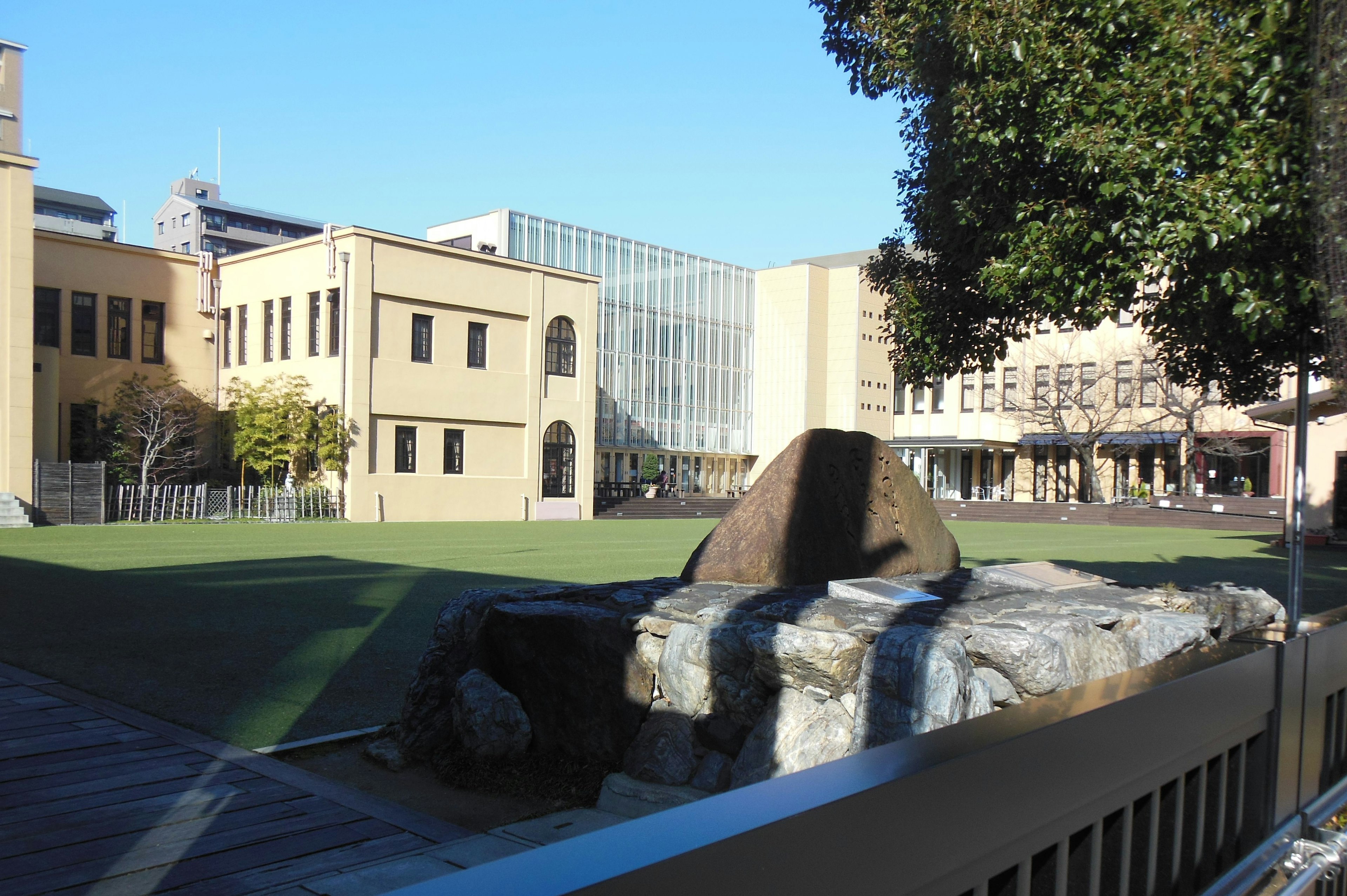 View of a park with green grass and stone sculptures near buildings