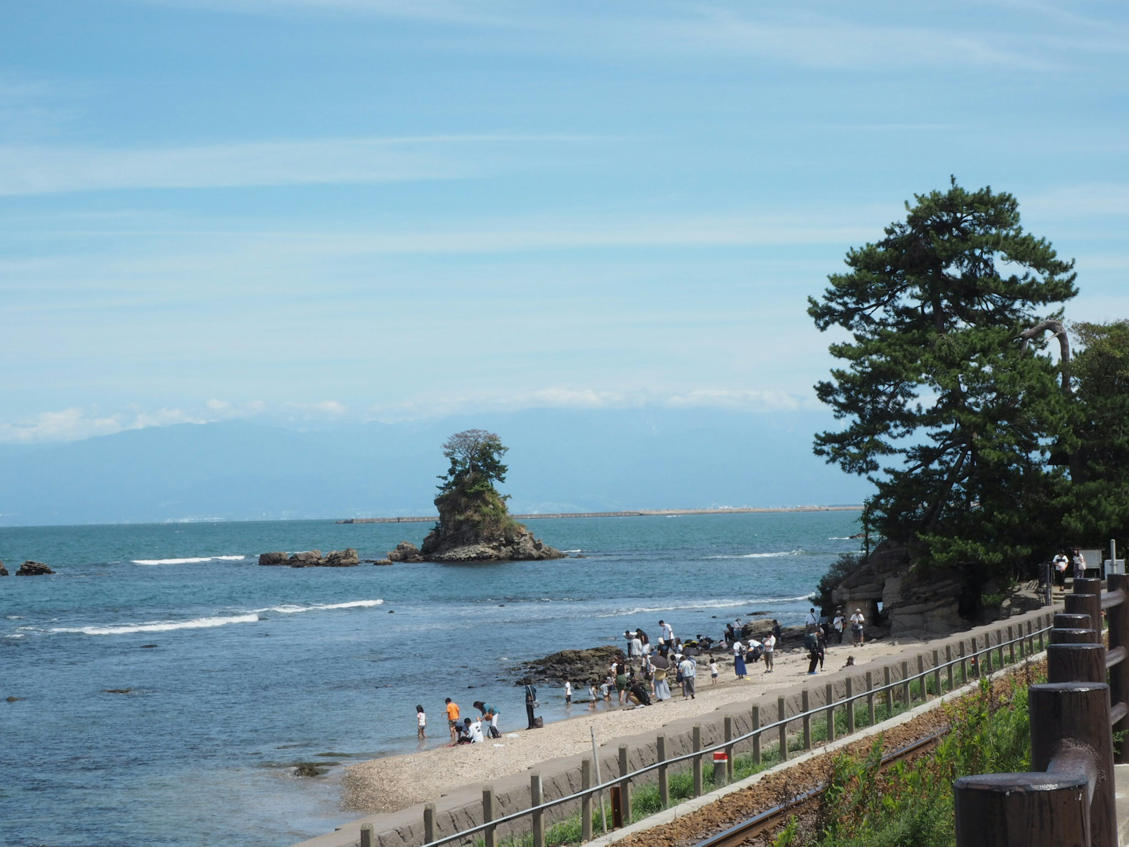 Pemandangan indah pantai dengan jalur pejalan kaki dan orang-orang menikmati pantai