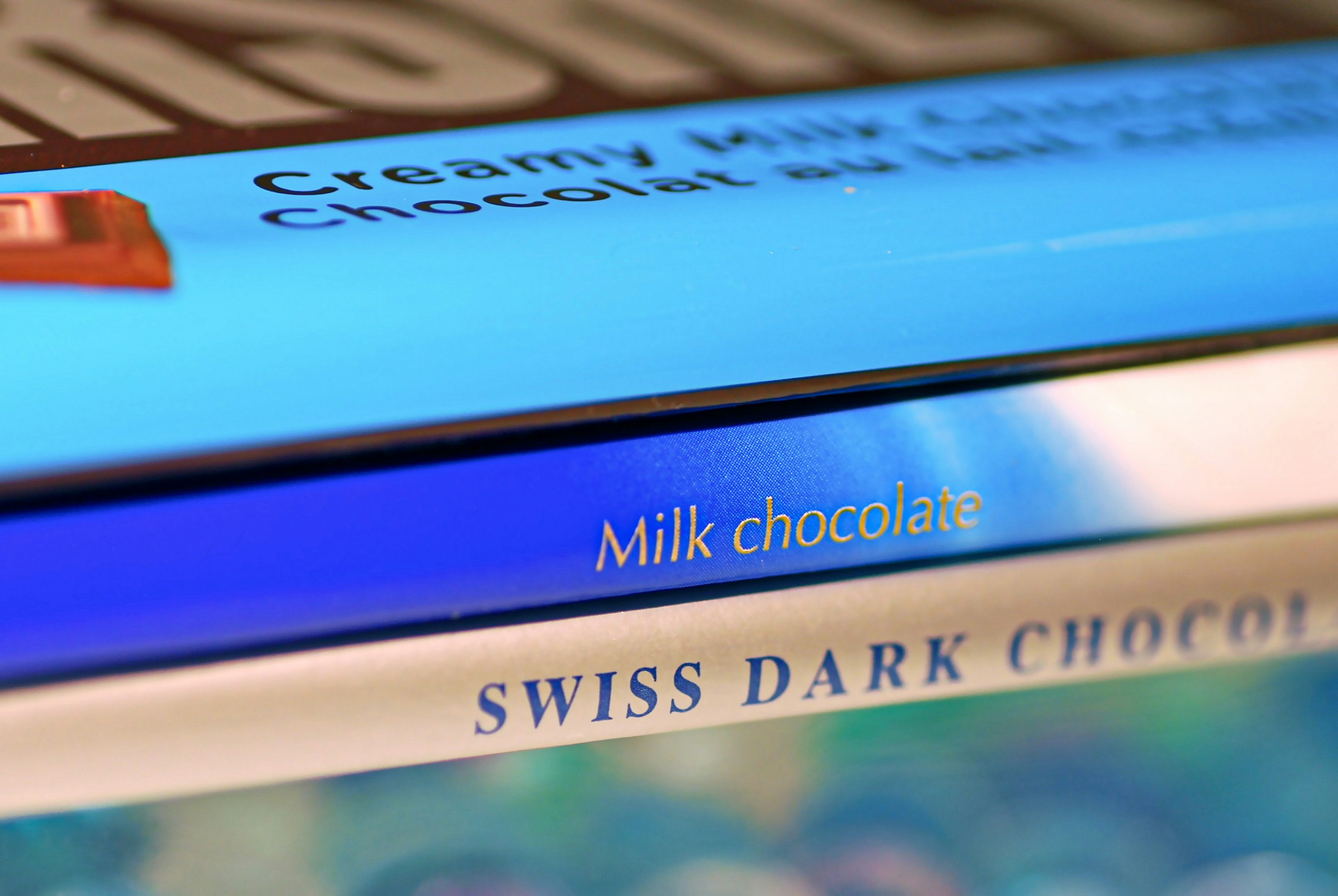 Tangkapan dekat kemasan cokelat susu dan cokelat hitam Swiss dengan warna biru