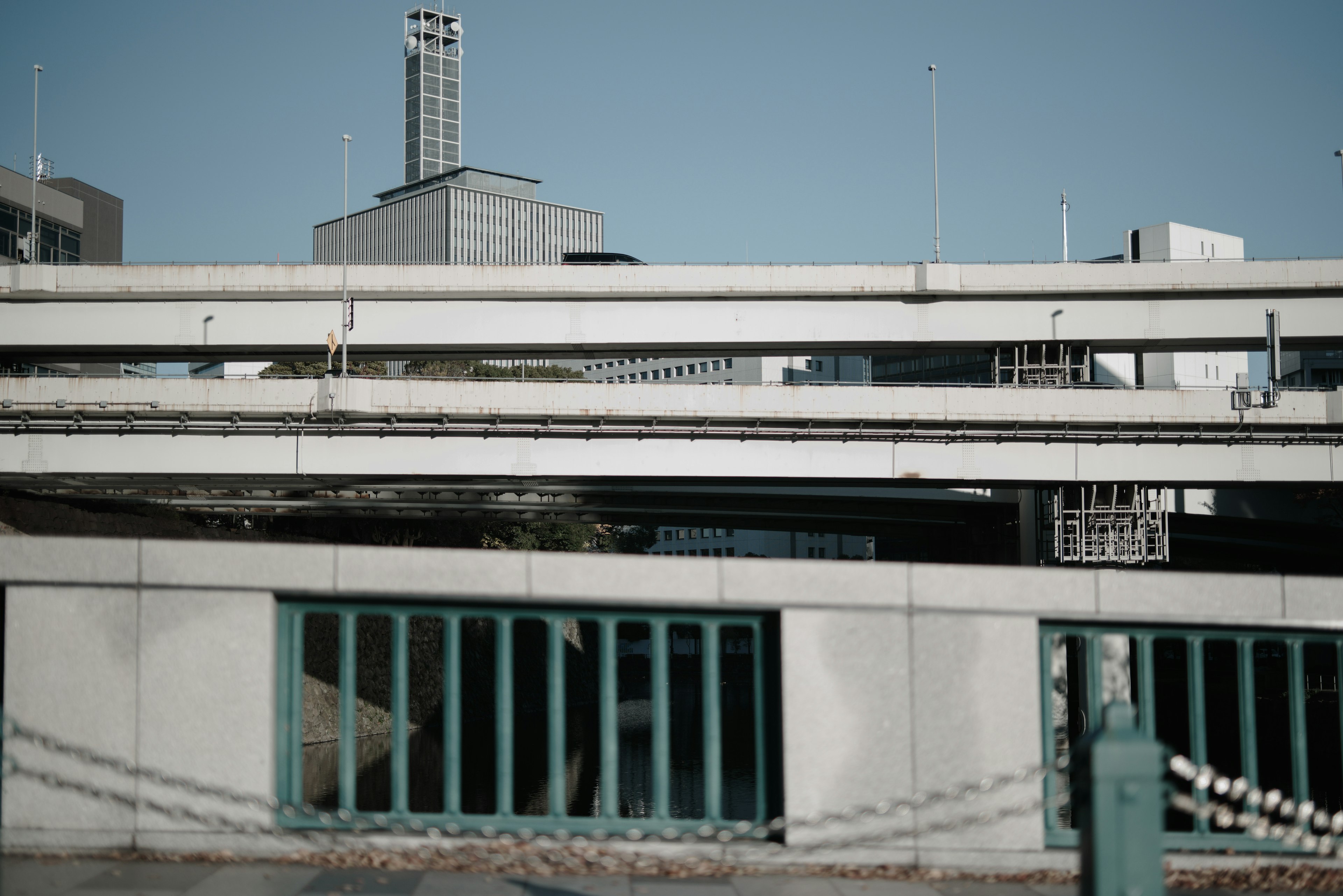 Fachada de un edificio moderno con ventanas verdes bajo un cielo azul