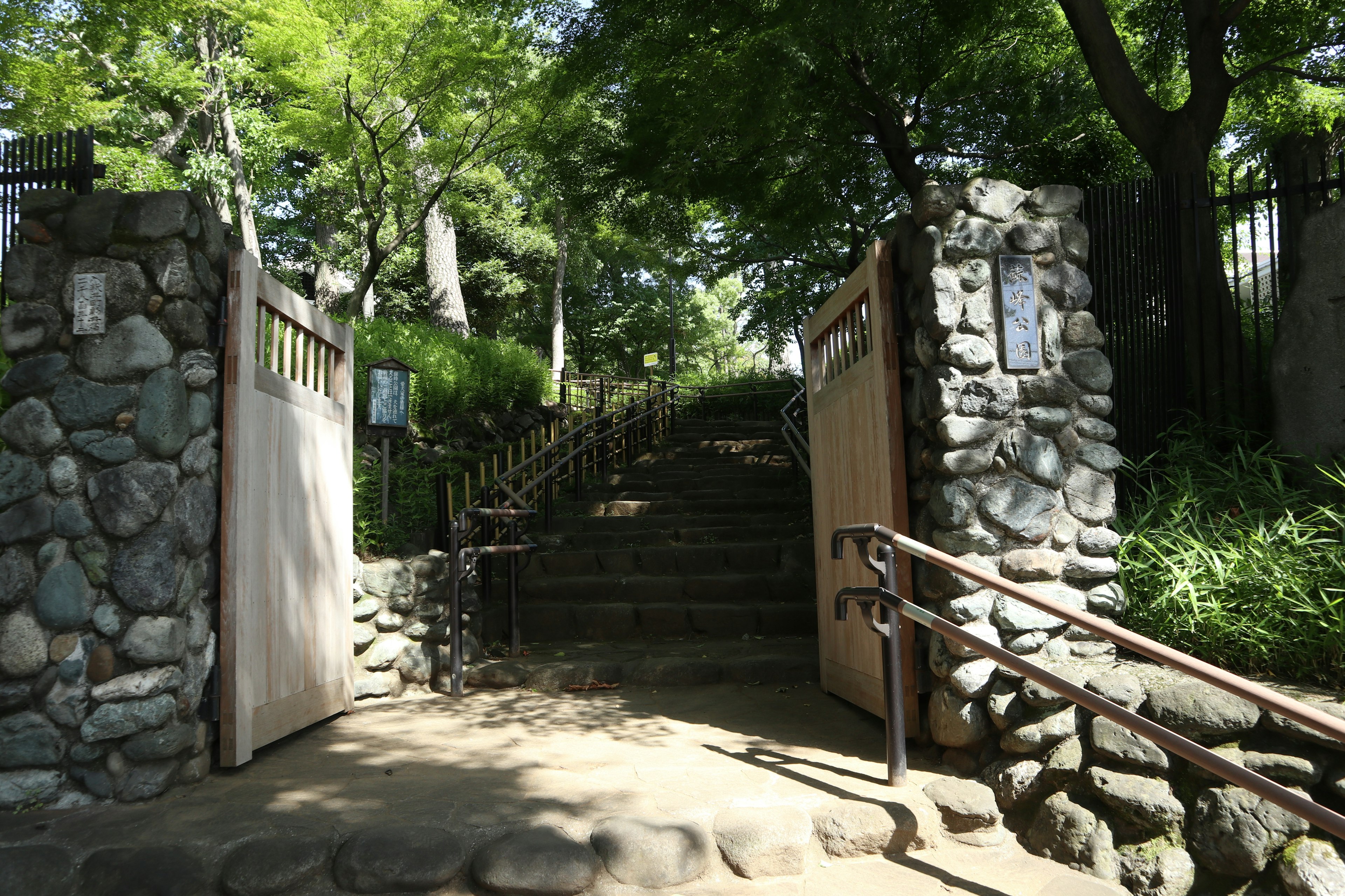 Stone gate leading to a staircase surrounded by lush greenery