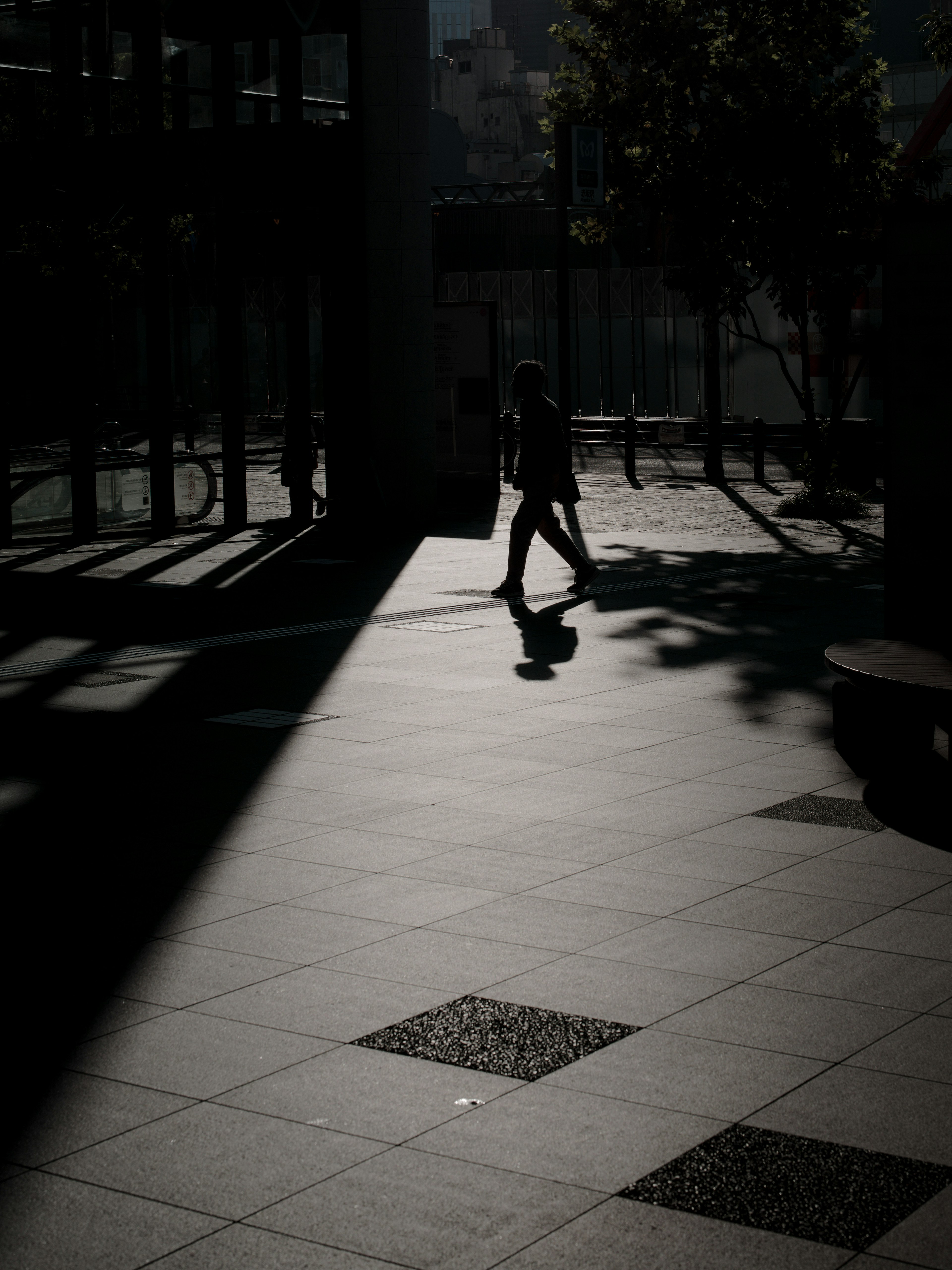 Silhouette d'une personne marchant dans les ombres sur un pavé urbain