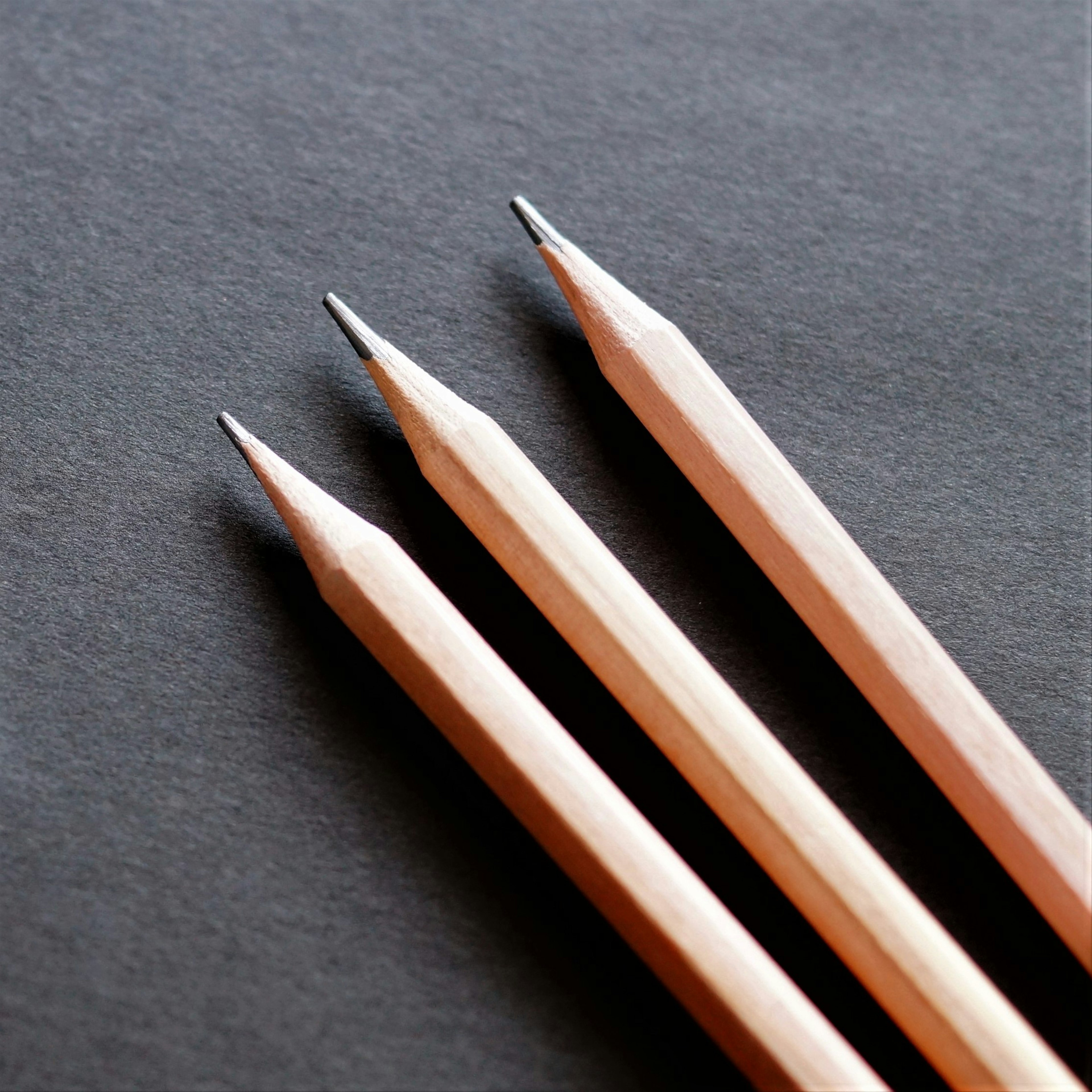 Three sharpened pencils positioned on a black background