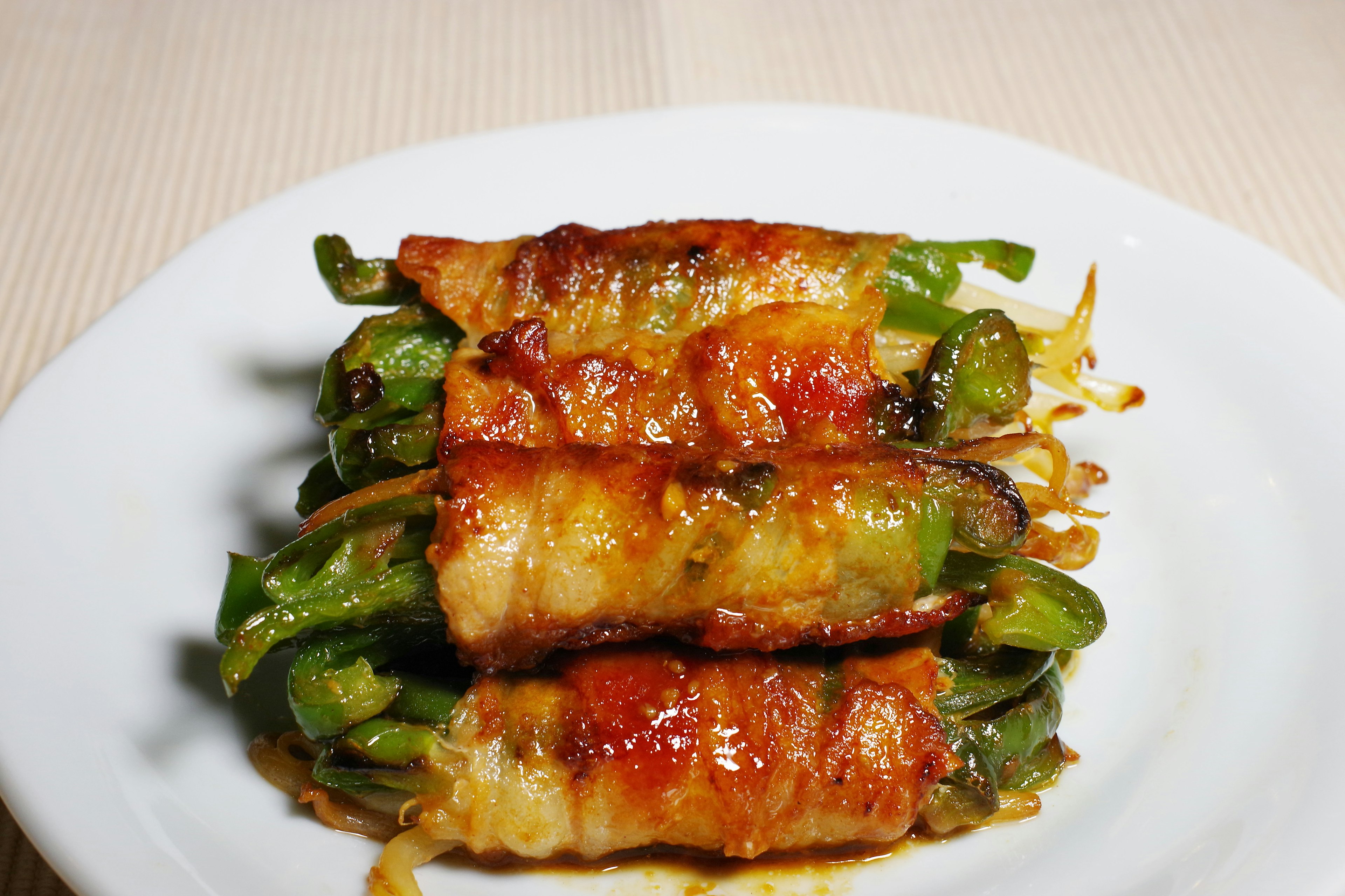 Grilled green onions wrapped in bacon served on a plate