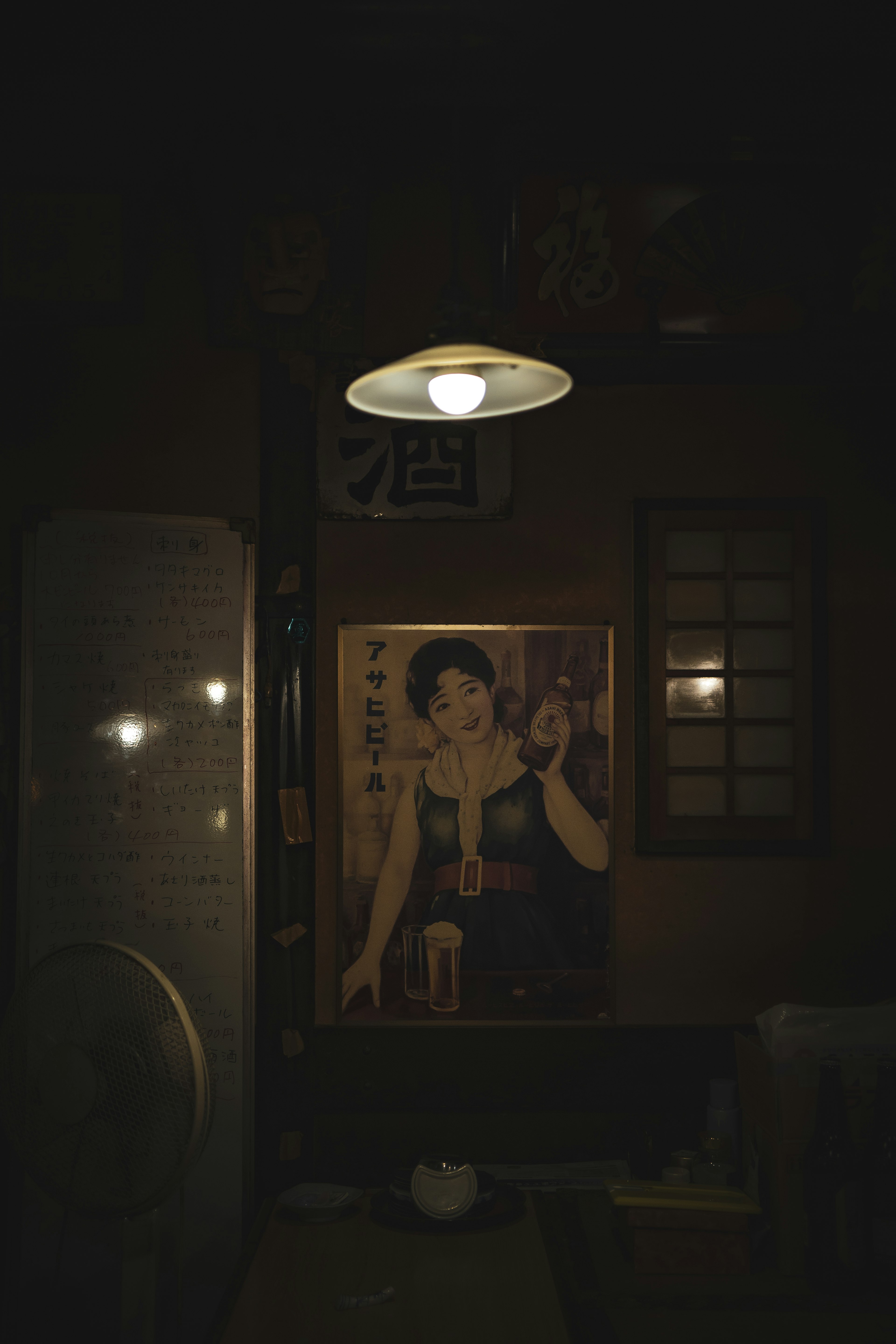 Dimly lit room featuring a hanging lamp and a portrait of a woman