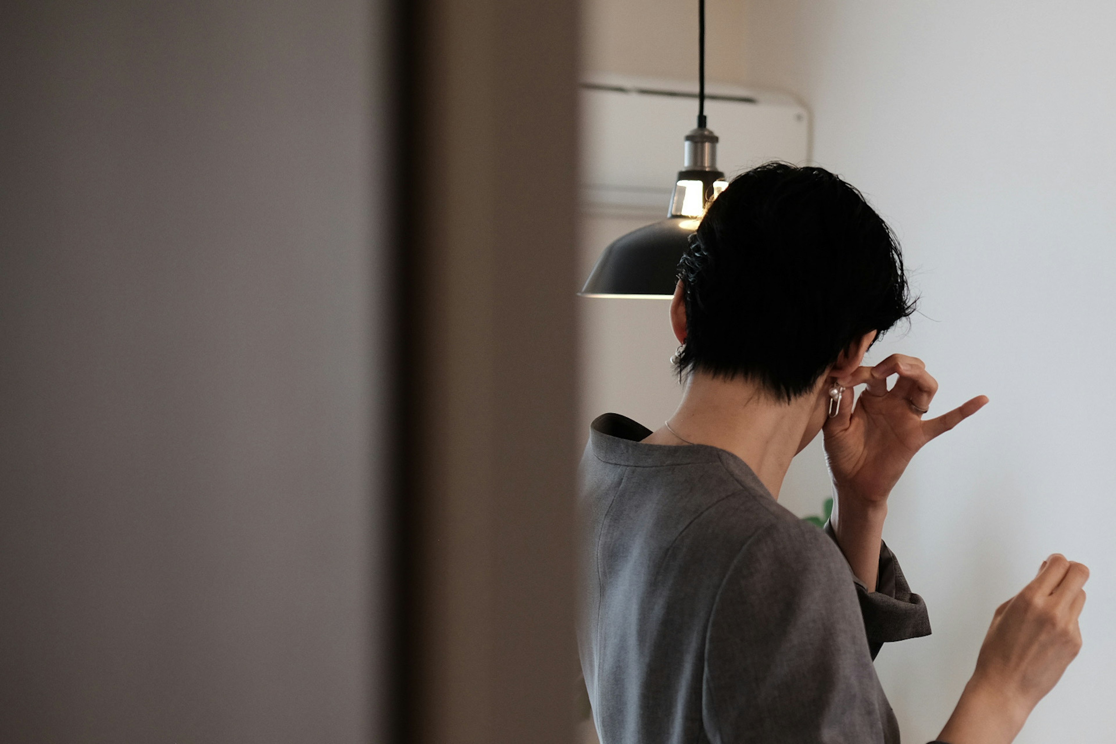 A woman adjusting her hair in front of a wall