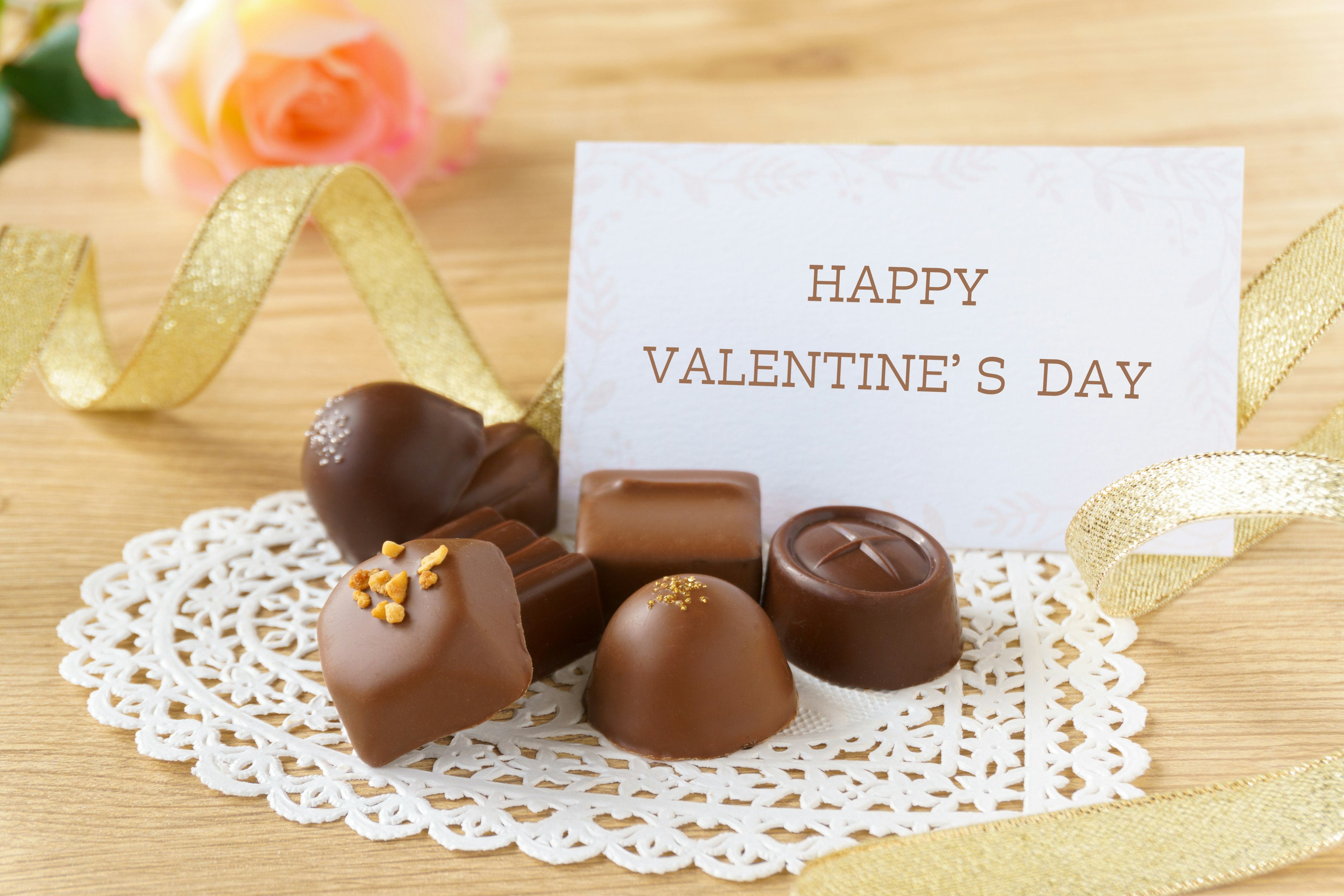 An assortment of chocolates arranged on a lace coaster with a Valentine's Day card