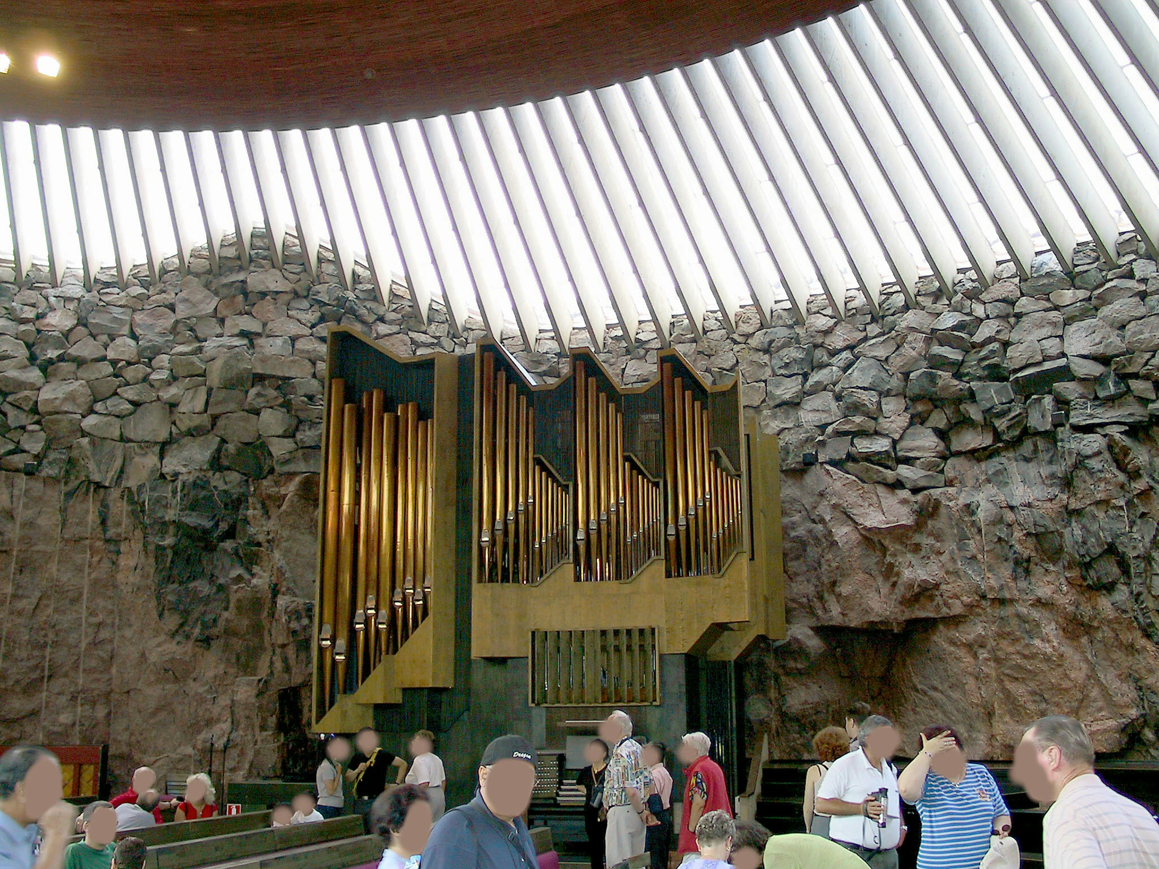 Interior of the Rock Church in Helsinki featuring an organ and visitors